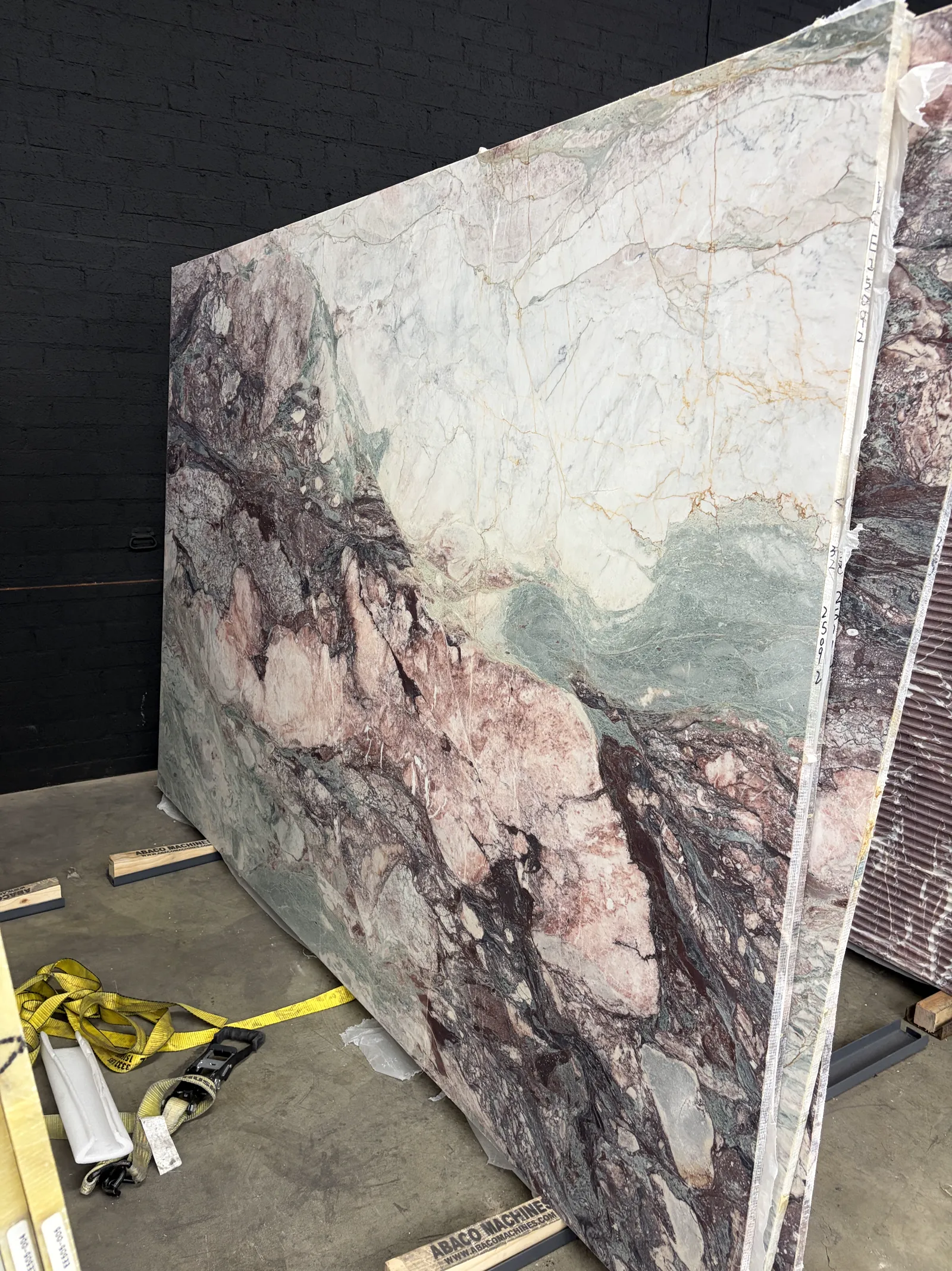 2cm Les Quatre Saisons Four Seasons honed marble slab standing full height on the floor at the Royal Stone yard — ivory fields breaking into blush pink, bordeaux, and sage green brecciated bands
