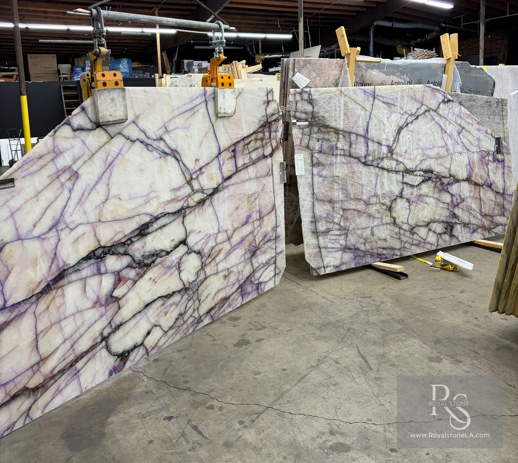 2cm Antolini Cristallo Trasviolet Treated DW654 slab bookmatched — two slabs laid open so the violet streaks meet on the seam — at the Royal Stone yard under racking lights