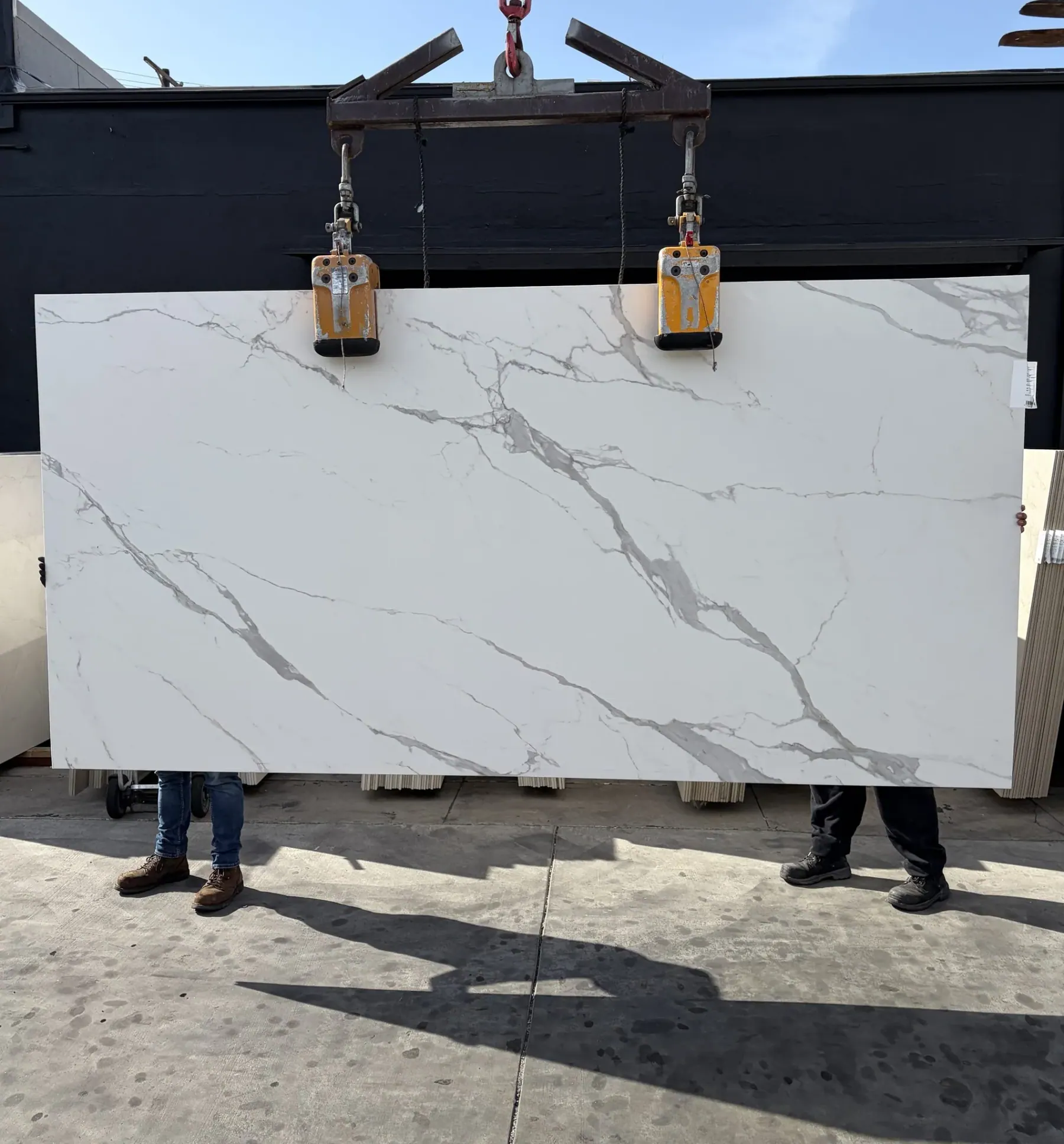 1.2cm ABK Statuario porcelain panel honed finish 63 by 126 inches lifted on a crane in the Royal Stone yard, bright cool white ground with diagonal grey veining and silvery secondary network, freshly imported from Italy