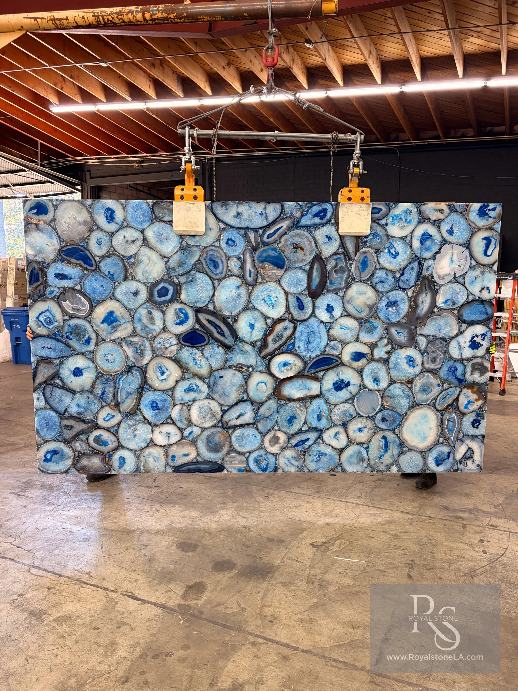 Full 76 by 128 inch slab of Antolini Agatona Blue semiprecious stone, Hamsa Blue polished, lot X250085, hanging from a crane at the Royal Stone warehouse in Los Angeles