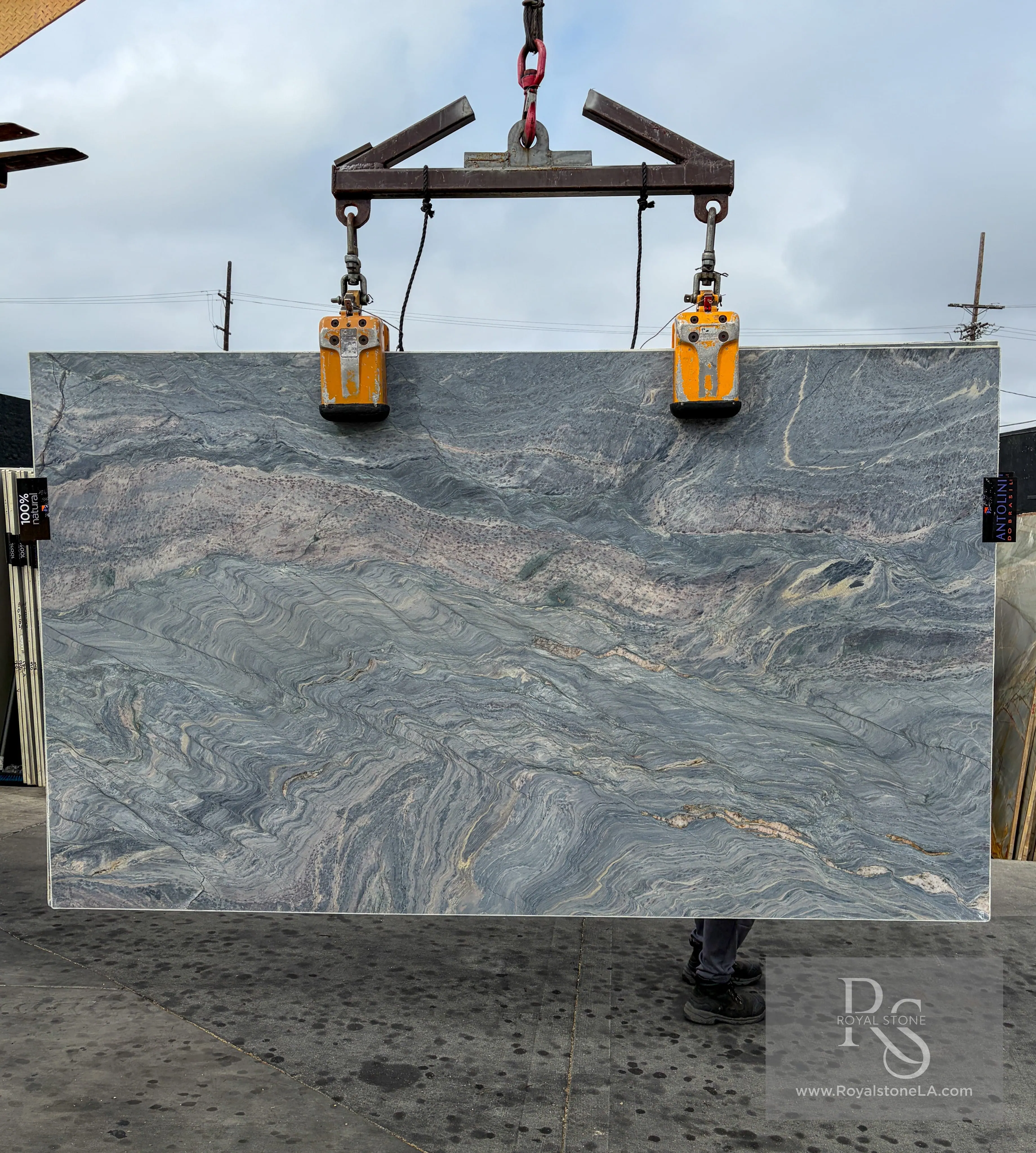 Antolini Blue Fusion Explosion AO777 quartzite slab on the crane at Royal Stone, deep steel-blue field with rolling pale gray and lavender veining