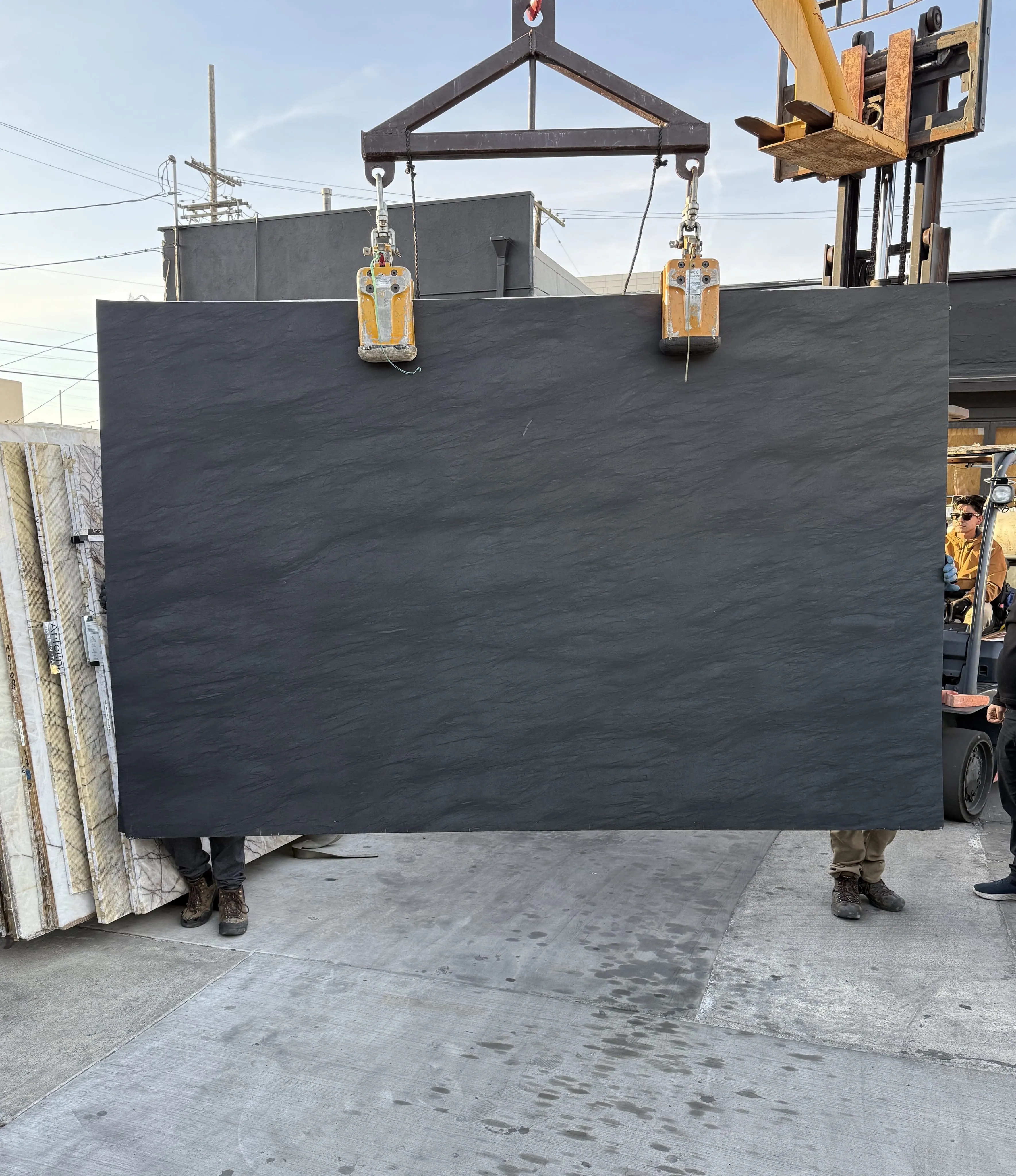 Antolini Bohemian Carbon Grey quartzite slab on the crane at Royal Stone, near-black field with a soft slate-like textured surface