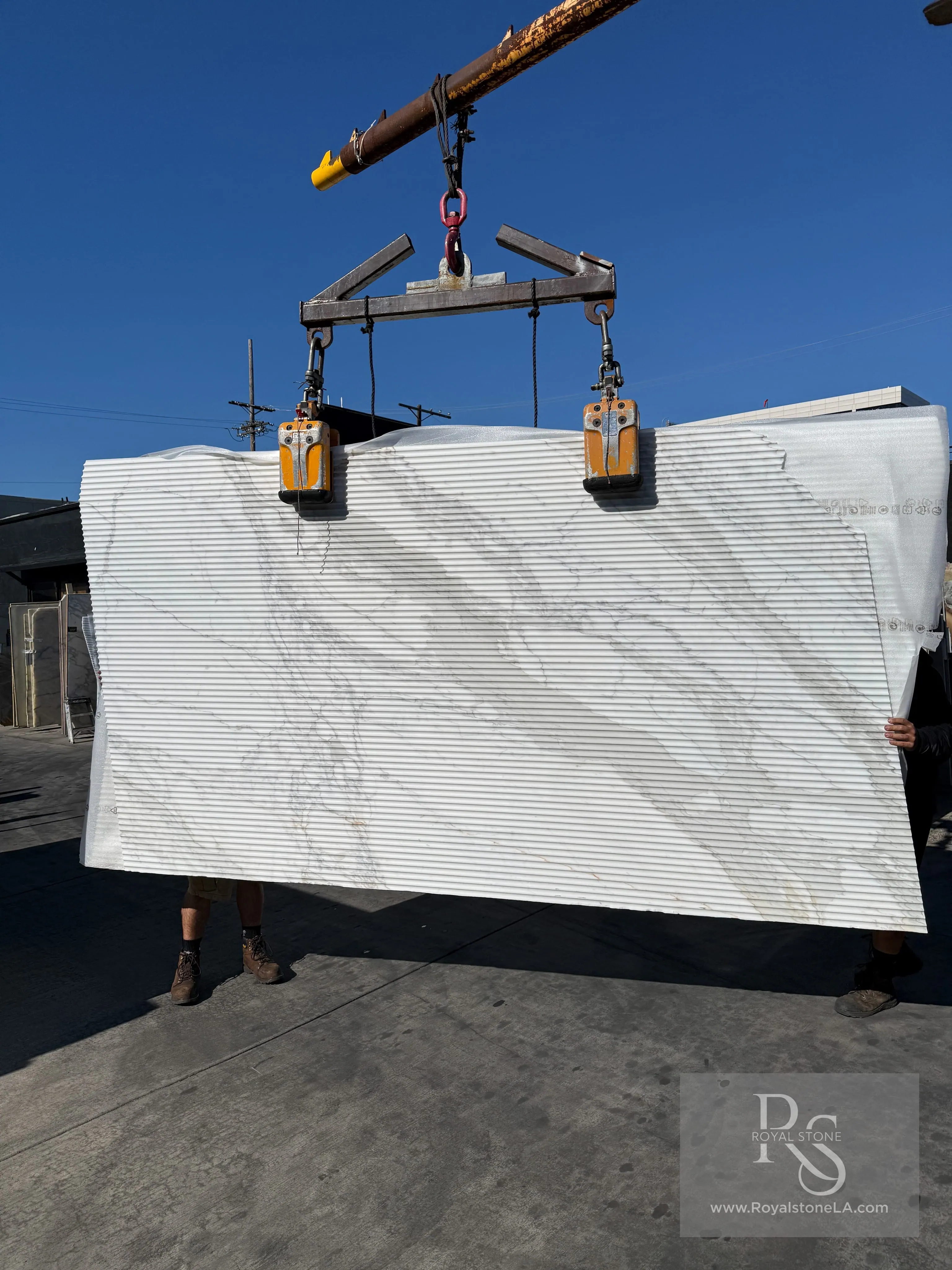 Antolini Calacatta Top Borghini YG575 marble slab with Flute Texture finish on the crane at Royal Stone, bright white field with soft grey-gold veining and close vertical ribbing