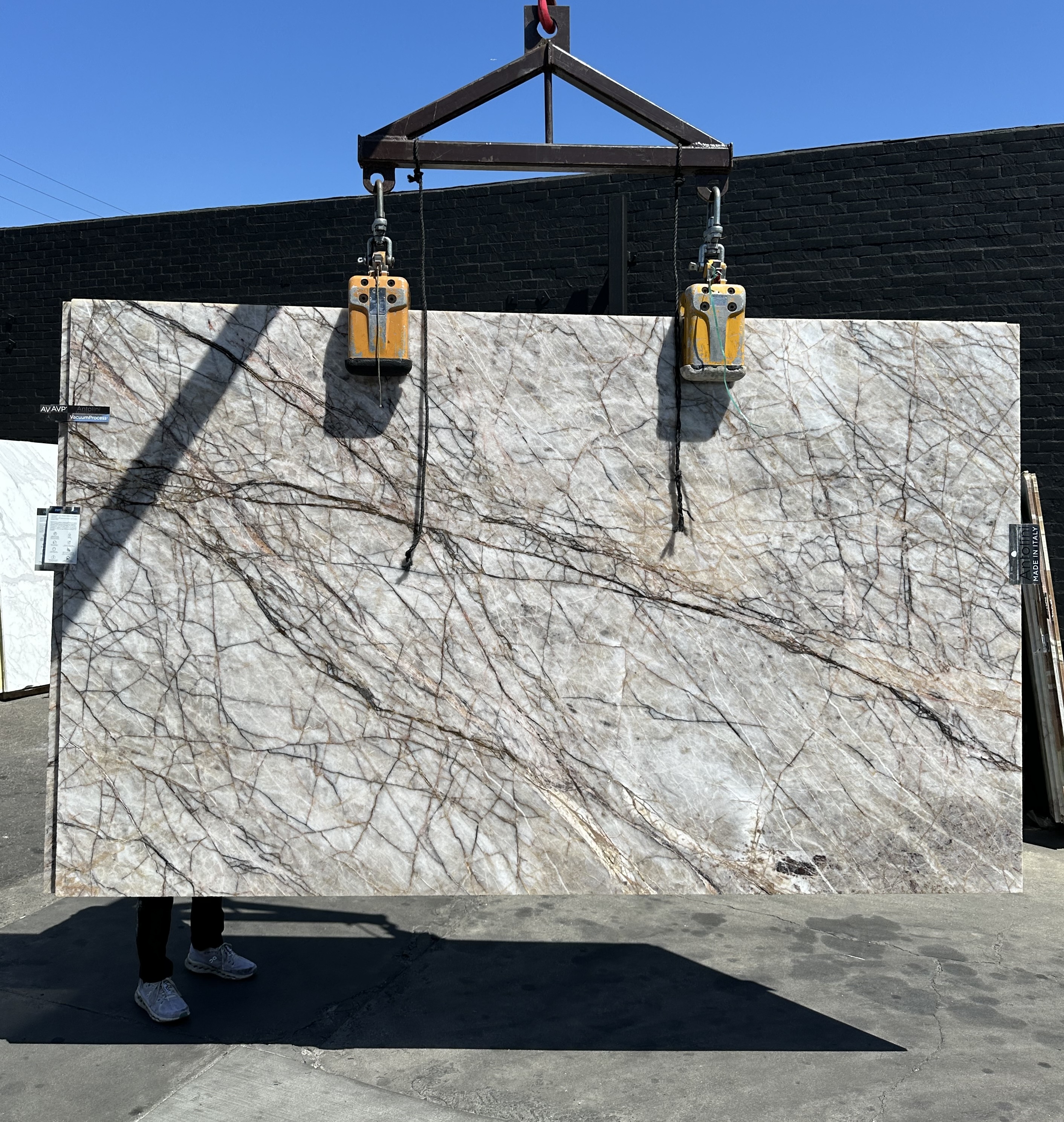 2cm Antolini Cristallo Roots quartzite slab, 75 by 122 inches, polished finish with translucent crystal field and fine cocoa and charcoal root-like veining, lifted by crane at Royal Stone in Los Angeles