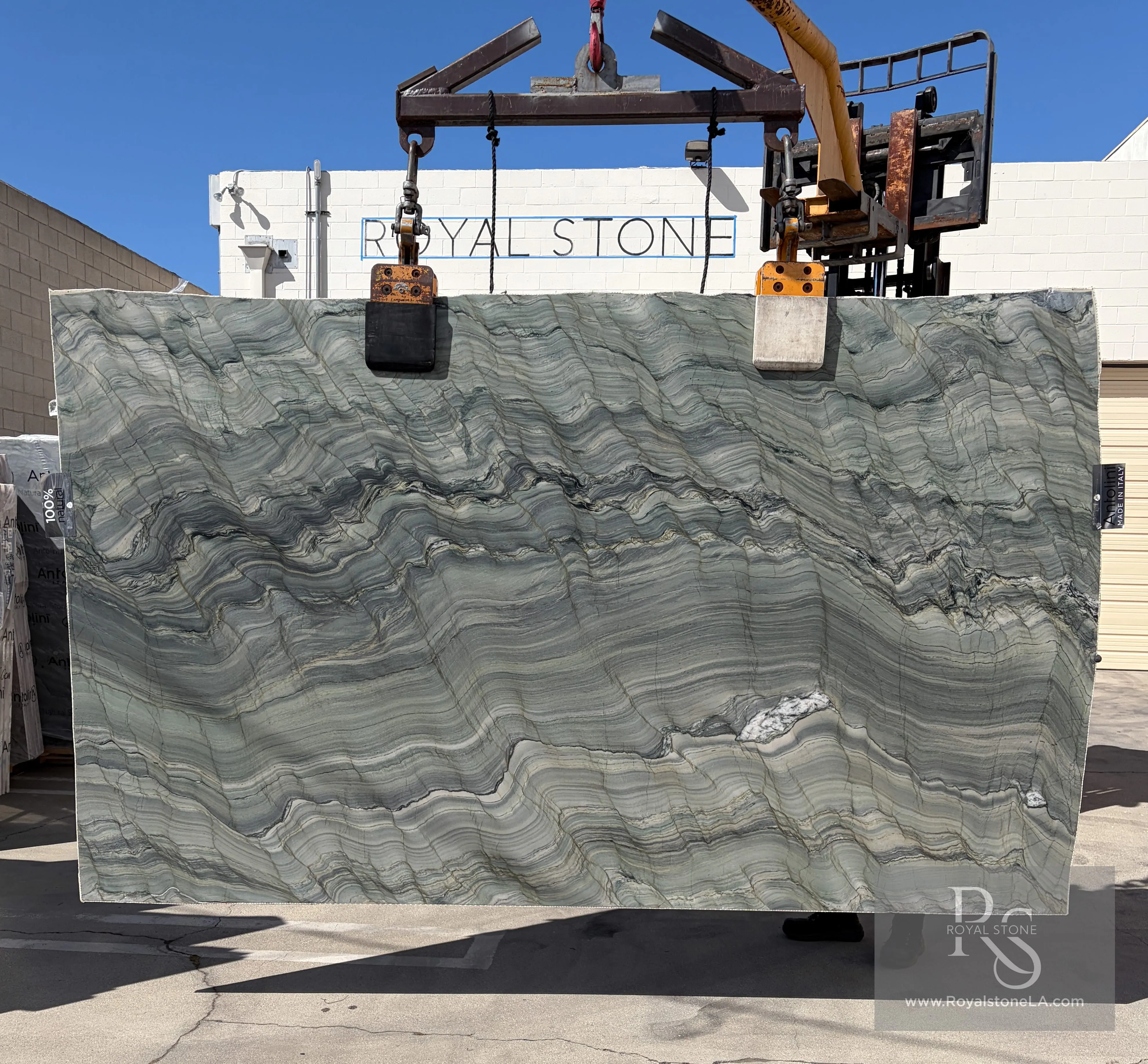 Antolini Fusion Green Wow ED963 quartzite slab lifted on the crane, soft sage-green field in horizontal bands with slate and ivory veining
