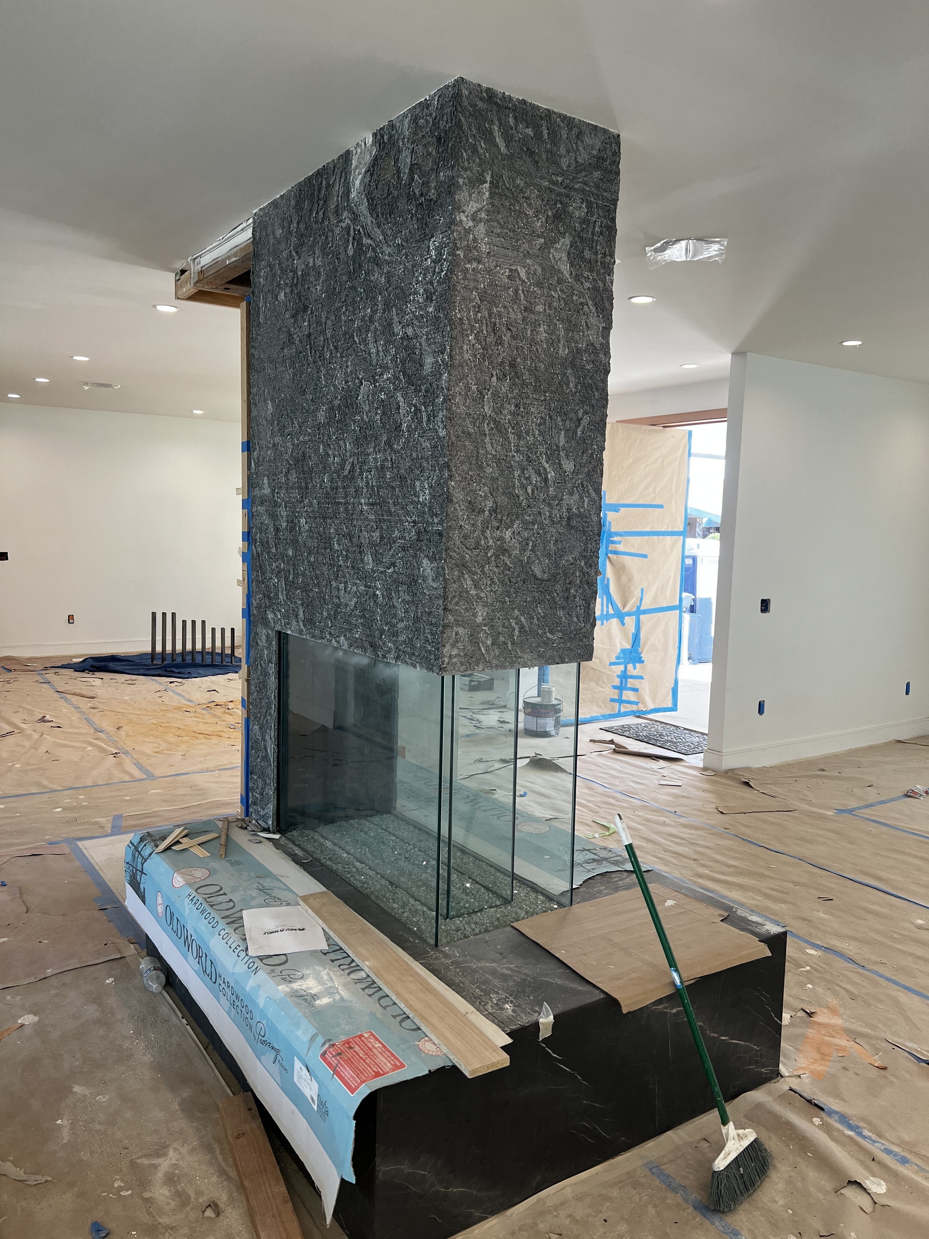 Side-angle view of the same Antolini Kosmos Quartzite Super Cleft Texture fireplace mass, showing the wrapped corner return reading as a single broken-rock monolith across two faces