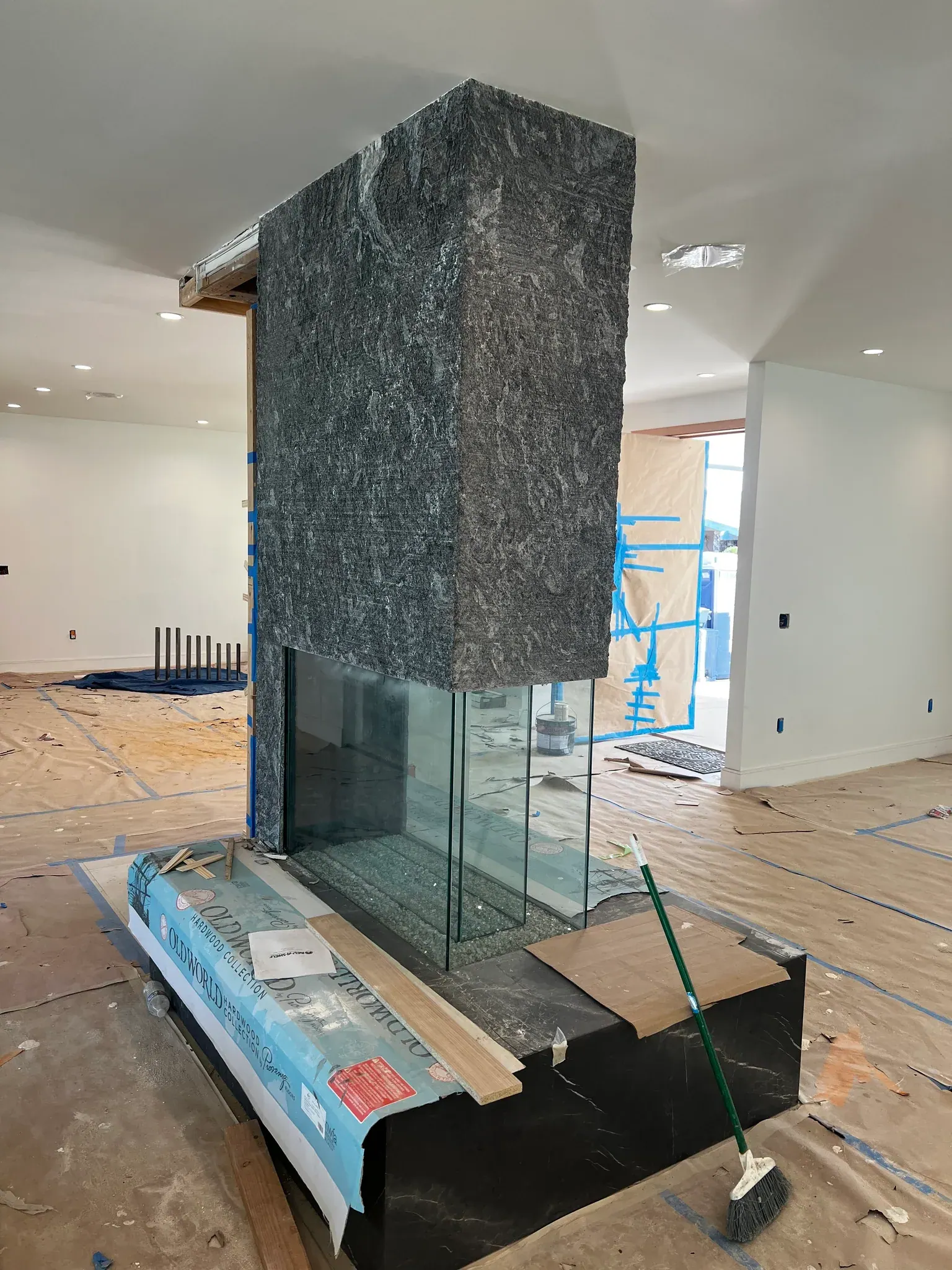 Side-angle view of the same Antolini Kosmos Quartzite Super Cleft Texture fireplace mass, showing the wrapped corner return reading as a single broken-rock monolith across two faces