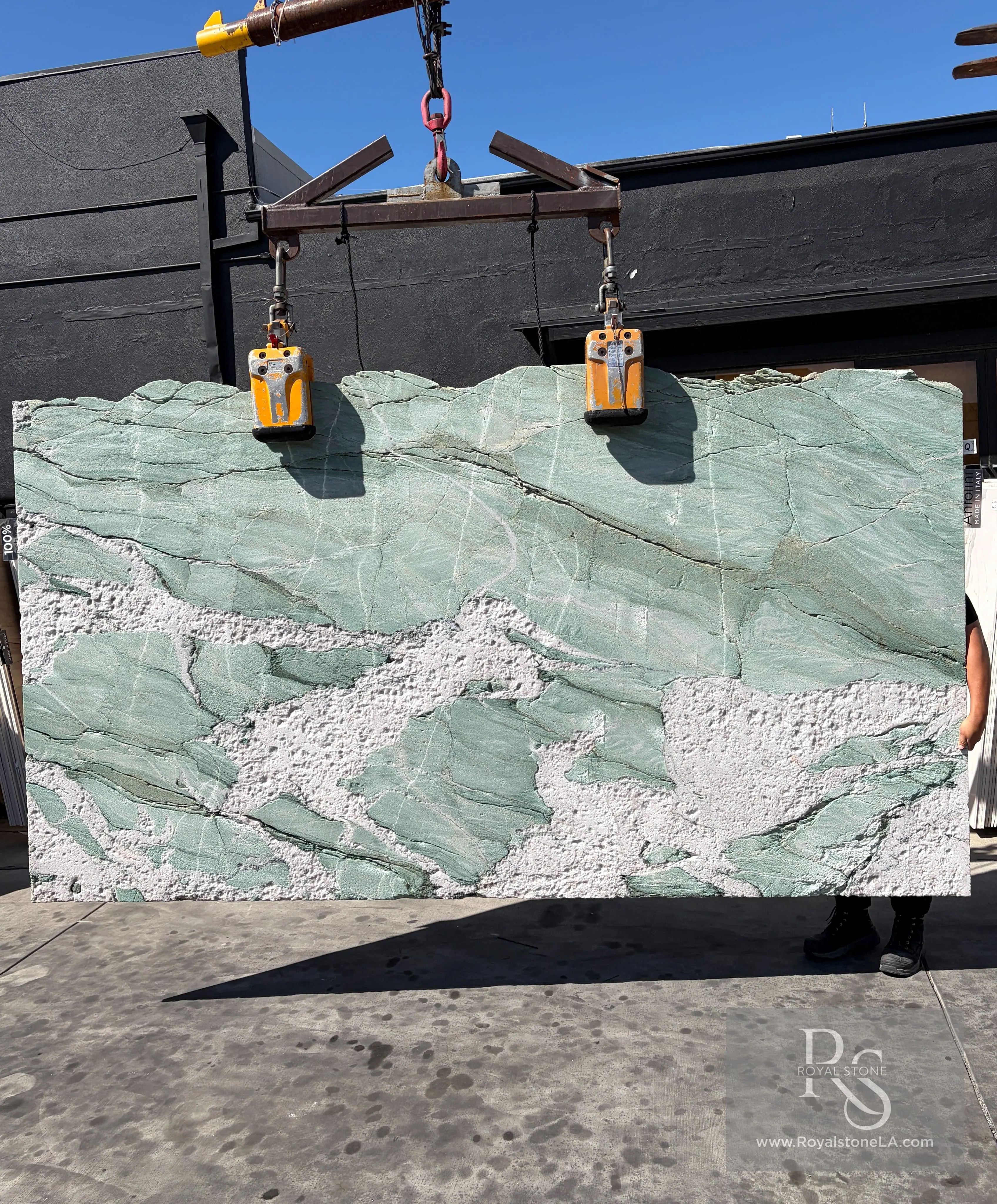Antolini Patagonia Aqua Green Cristallo DX910 quartzite slab lifted on the crane, aqua-green field with heavy hard-rock textural relief