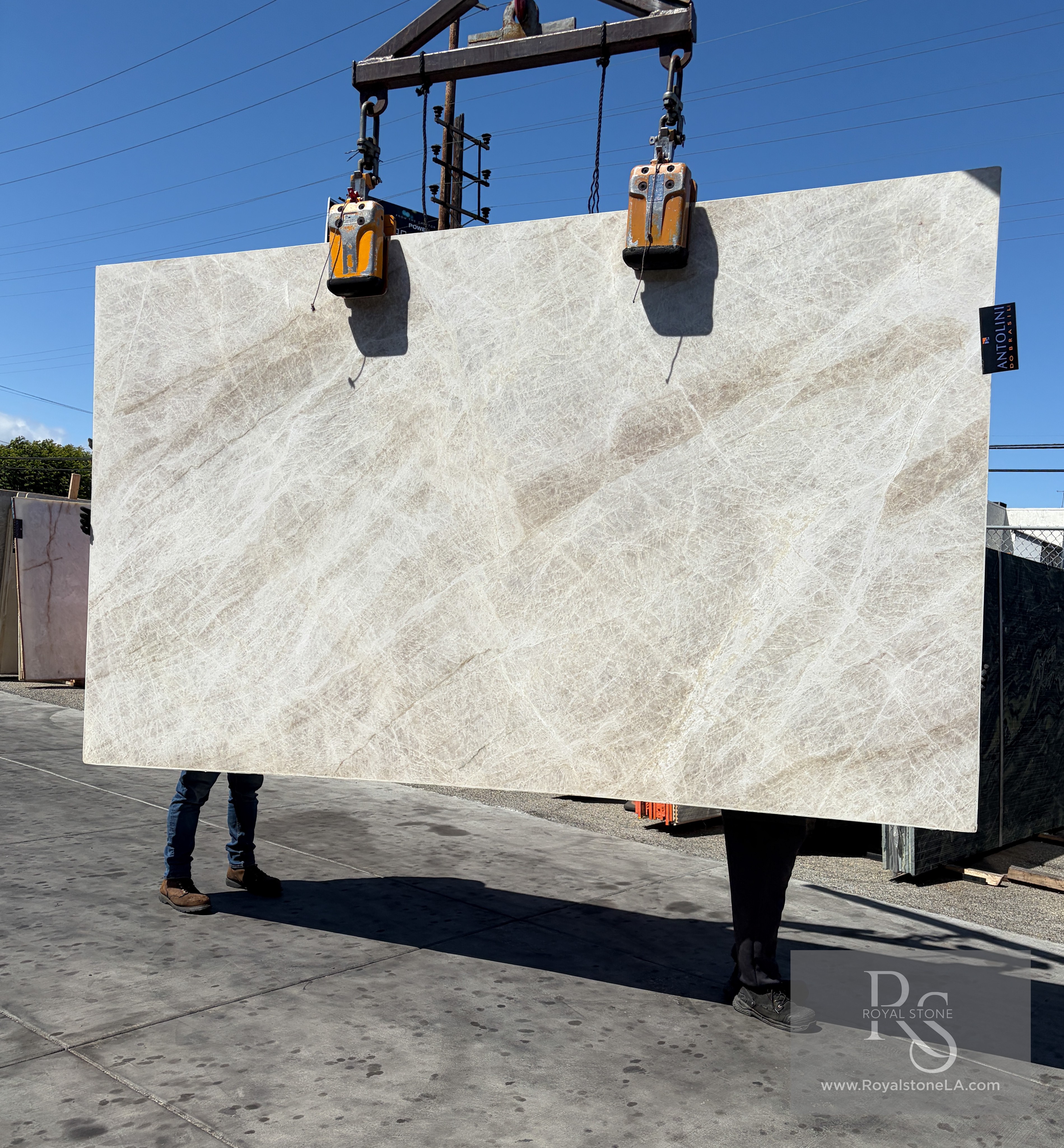 Antolini Taj Mahal Select polished quartzite slab on the crane against blue sky, 79 by 133 inches, soft champagne field with diagonal crystalline drift