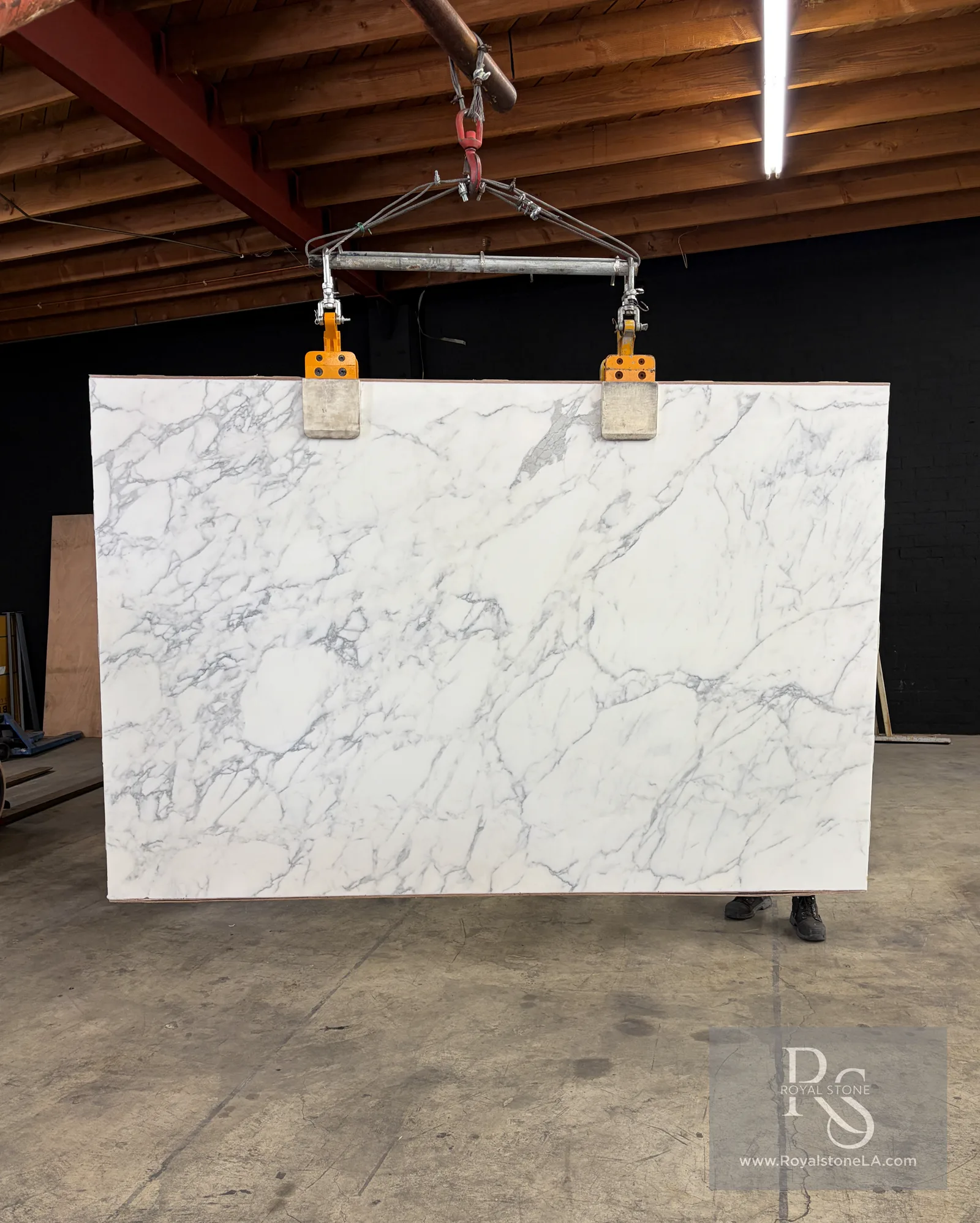 2cm Calacatta Borghini Extra Lot 15728 honed marble slab, 78 by 120 inches, bright white field crossed by bold gray veining threaded with gold, hanging on the clamps at the Royal Stone yard in Los Angeles