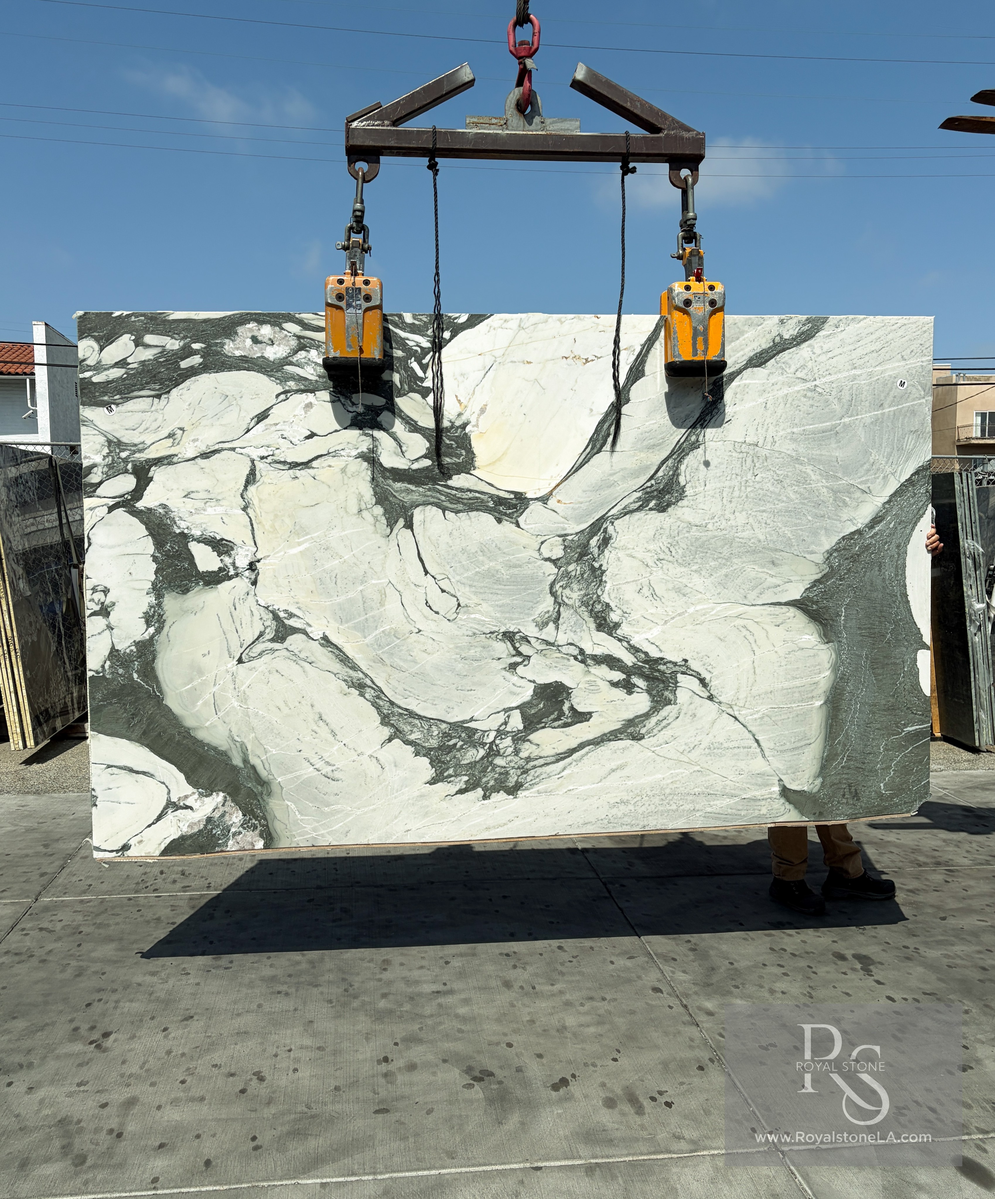 2cm Calacatta Green Picasso honed marble slab, 78 by 119 inches, with sweeping forest-green veining over an ivory white background, lifted on the vacuum gantry at the Royal Stone Los Angeles yard