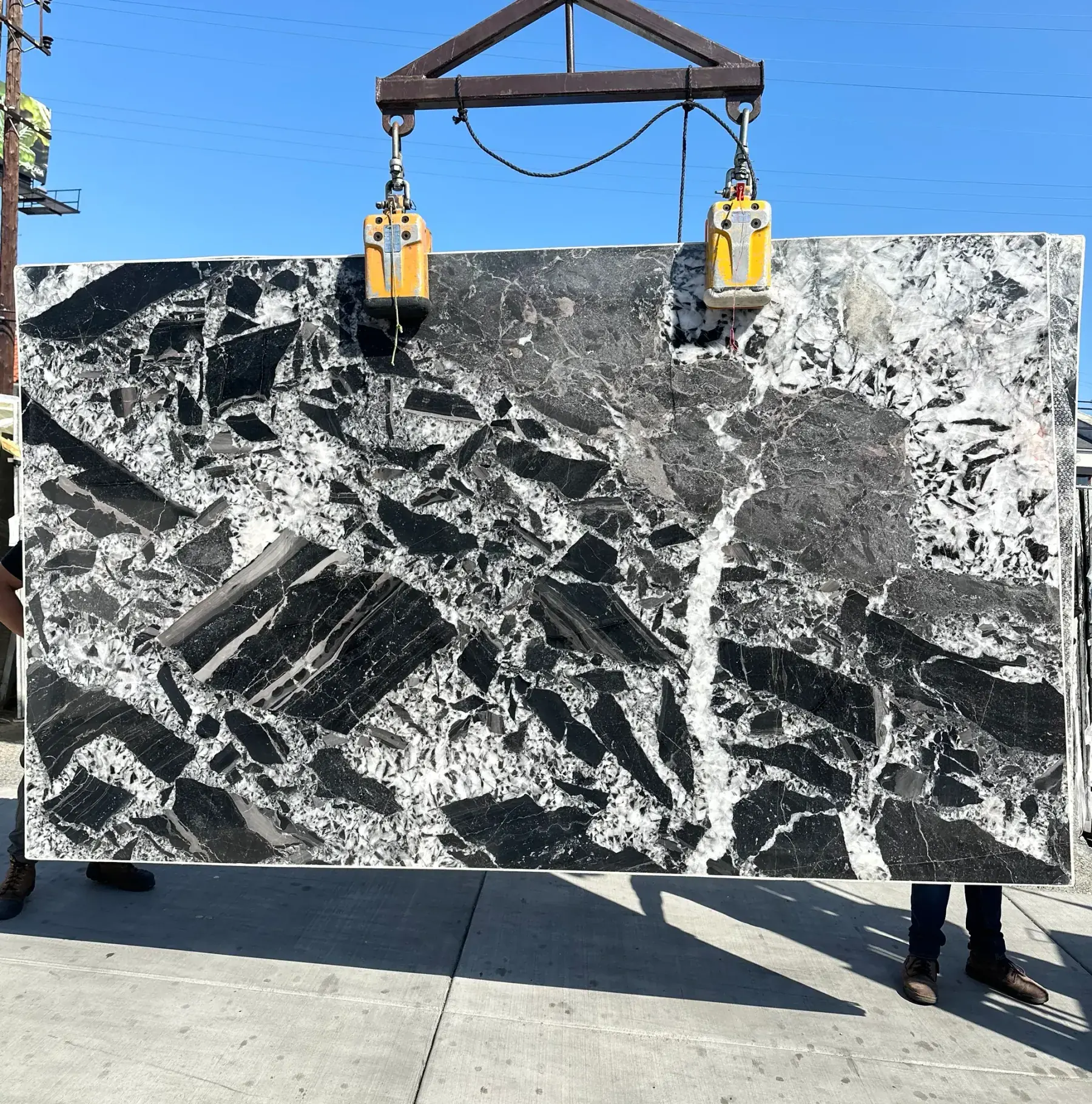 Antolini Cristallo Nero quartzite slab on the crane, fractured black and charcoal blocks suspended in white crystalline quartz matrix, polished finish, 78 by 129 inches