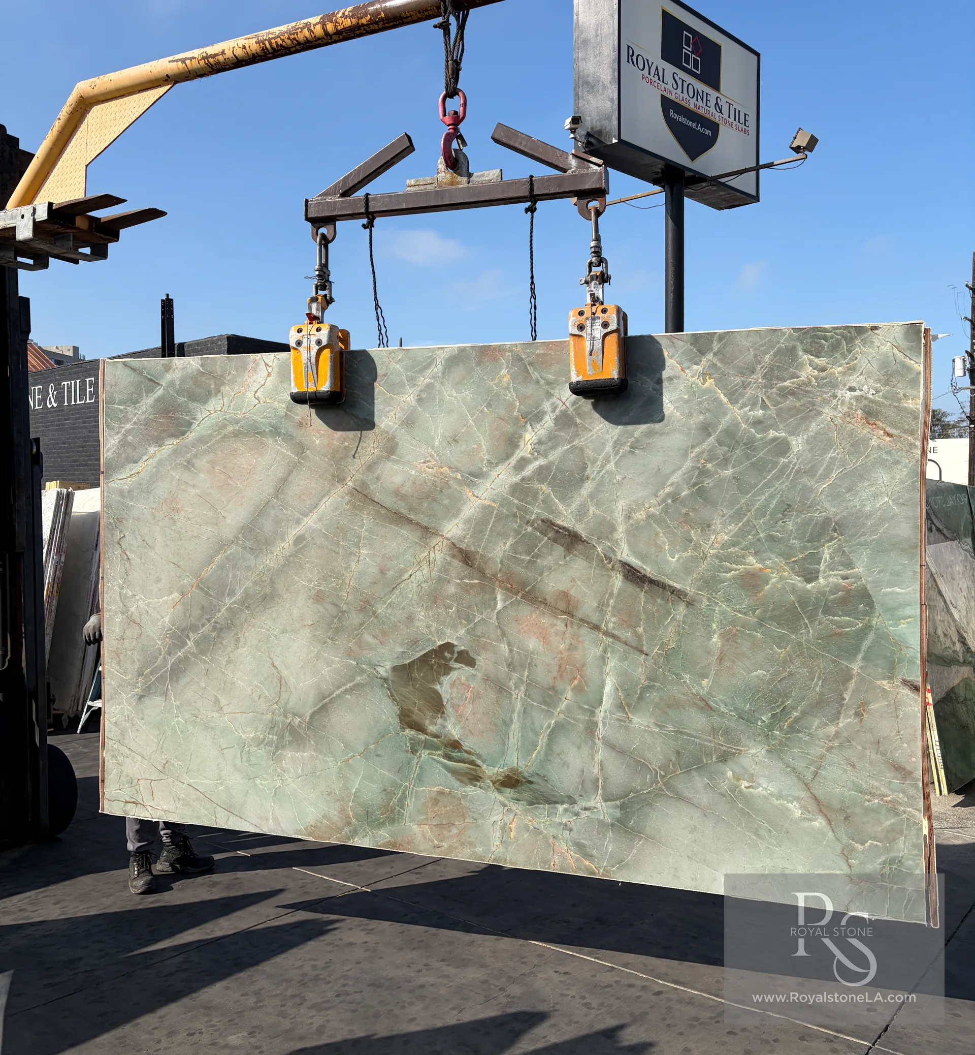 2cm Emerald Quartzite Jadore honed slab, 79 by 130 inches from Bassi Italy — pale jade and emerald-green field with rose, copper and faint gold veining drawn across the body, lifted on overhead crane at the Royal Stone yard in Los Angeles