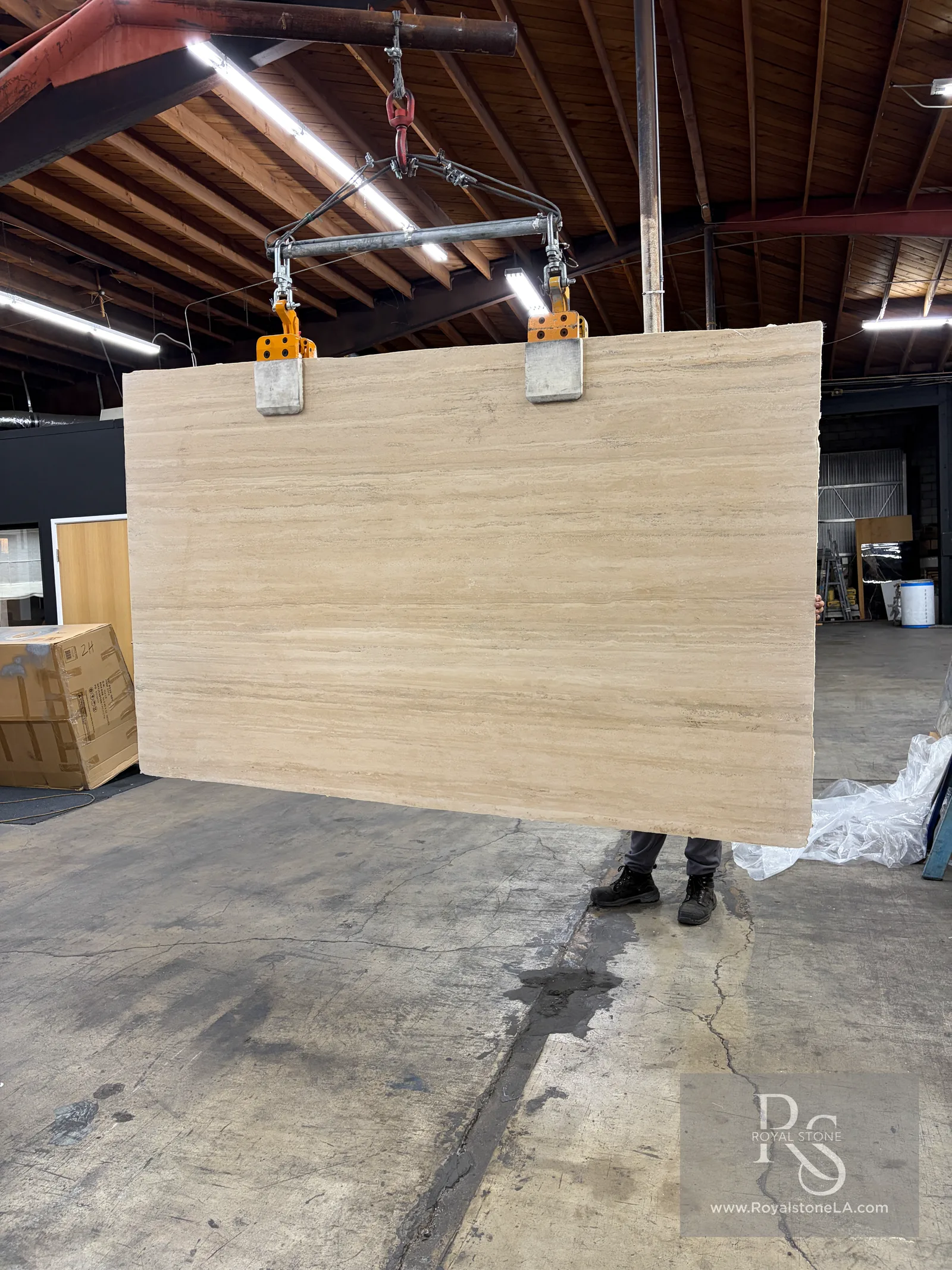 Super premium Italian Roman Travertine slab, vein cut, honed and filled, hanging on the clamps at Royal Stone Los Angeles, 72 by 116 inches