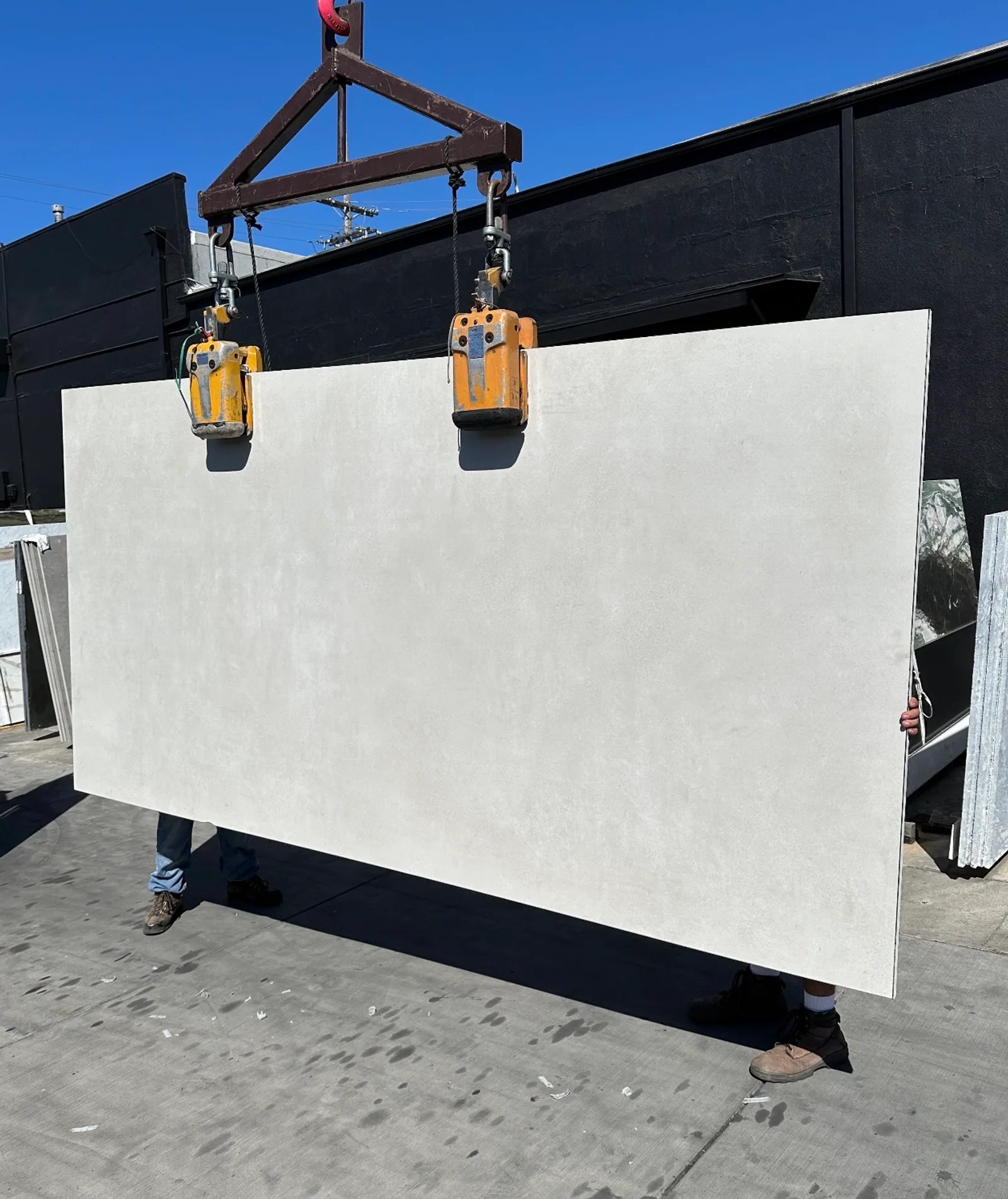 1.2cm Level by Emil Concrete White matte porcelain panel 63 by 126 inches lifted on a crane in the Royal Stone yard, warm off-white field with soft cement-like microvariation, freshly imported from Italy