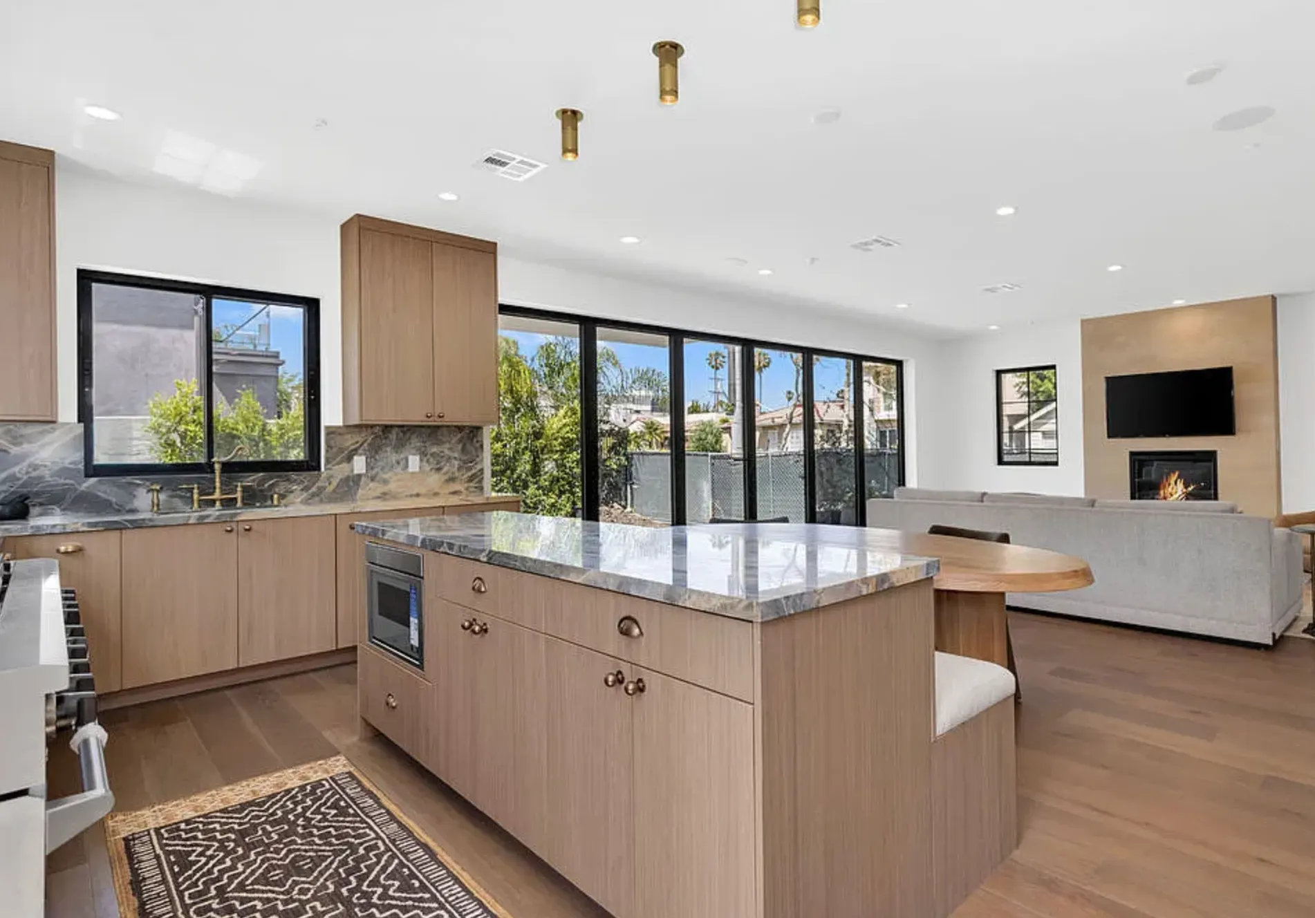 Wide view of the Portoro Gold Tempest polished marble kitchen island and adjoining living space at 8671 Clifton Way