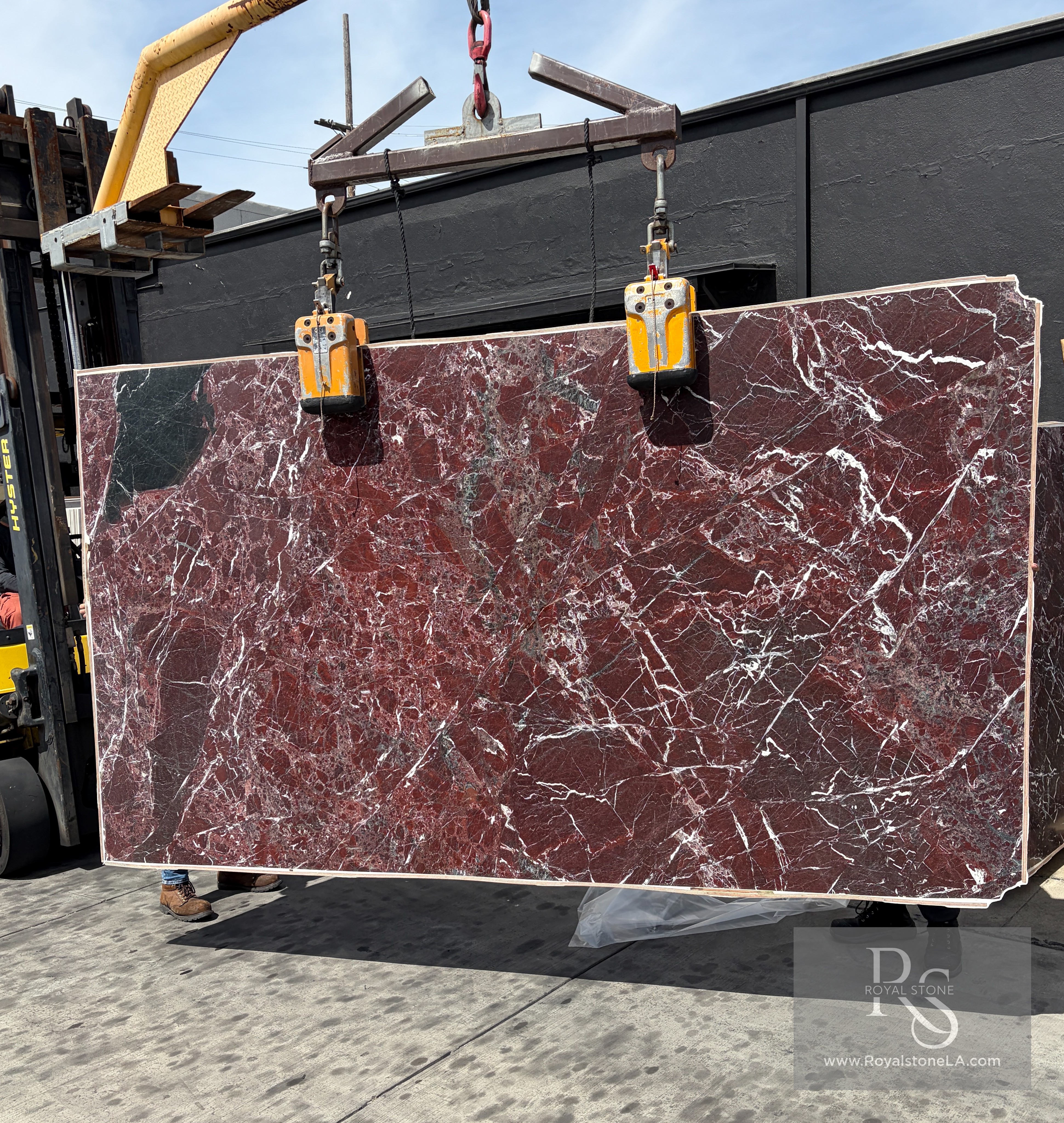 2cm Rosso Lepanto marble slab, 71 by 126 inches, leathered finish with deep oxblood and burgundy field, bright white calcite veining, and black inclusions, lifted by crane at Royal Stone in Los Angeles