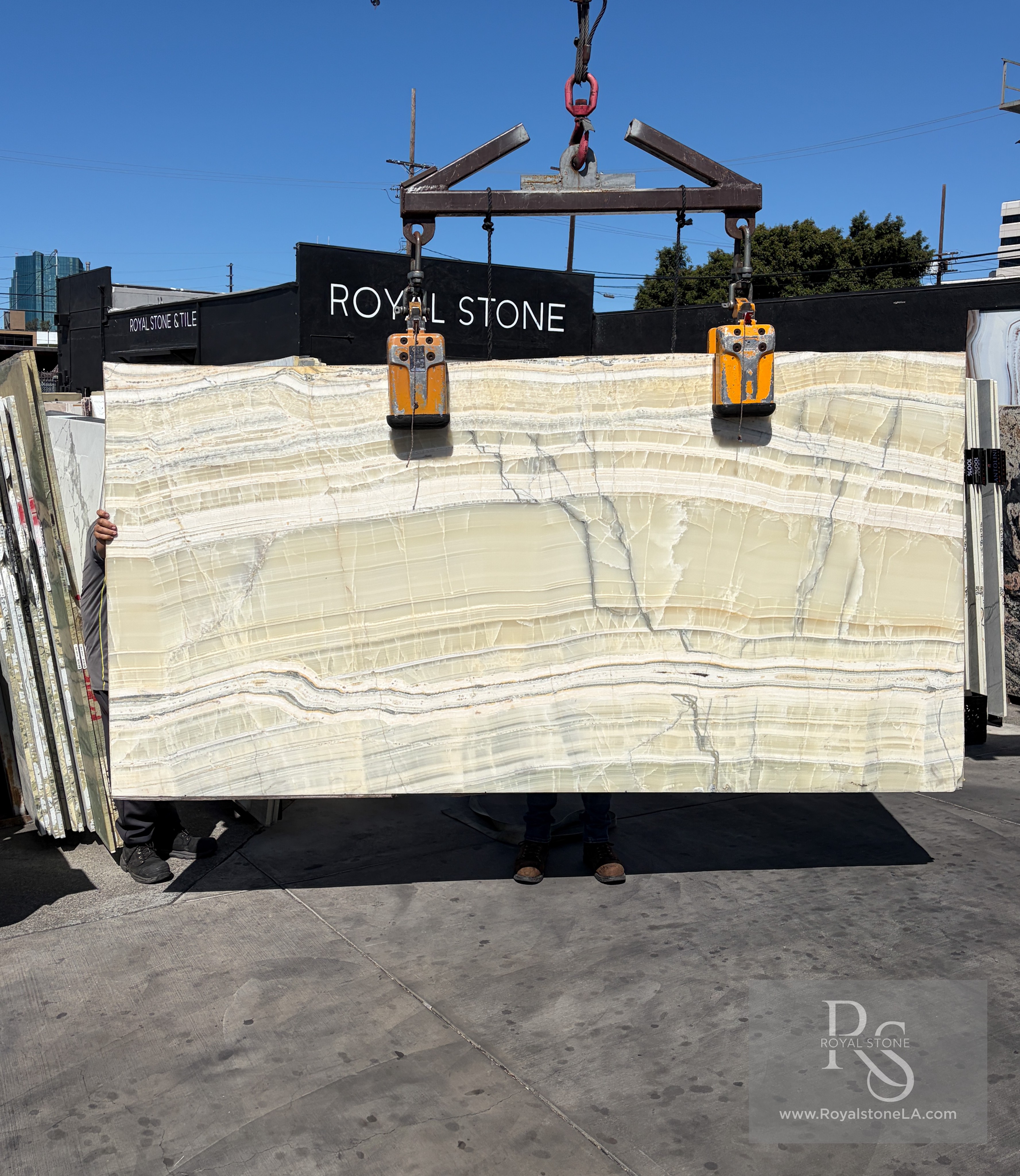 Vanilla Sage vein-cut onyx slab polished at 62 by 114 inches lifted on the crane at Royal Stone Los Angeles, translucent cream and pale celadon stratified body