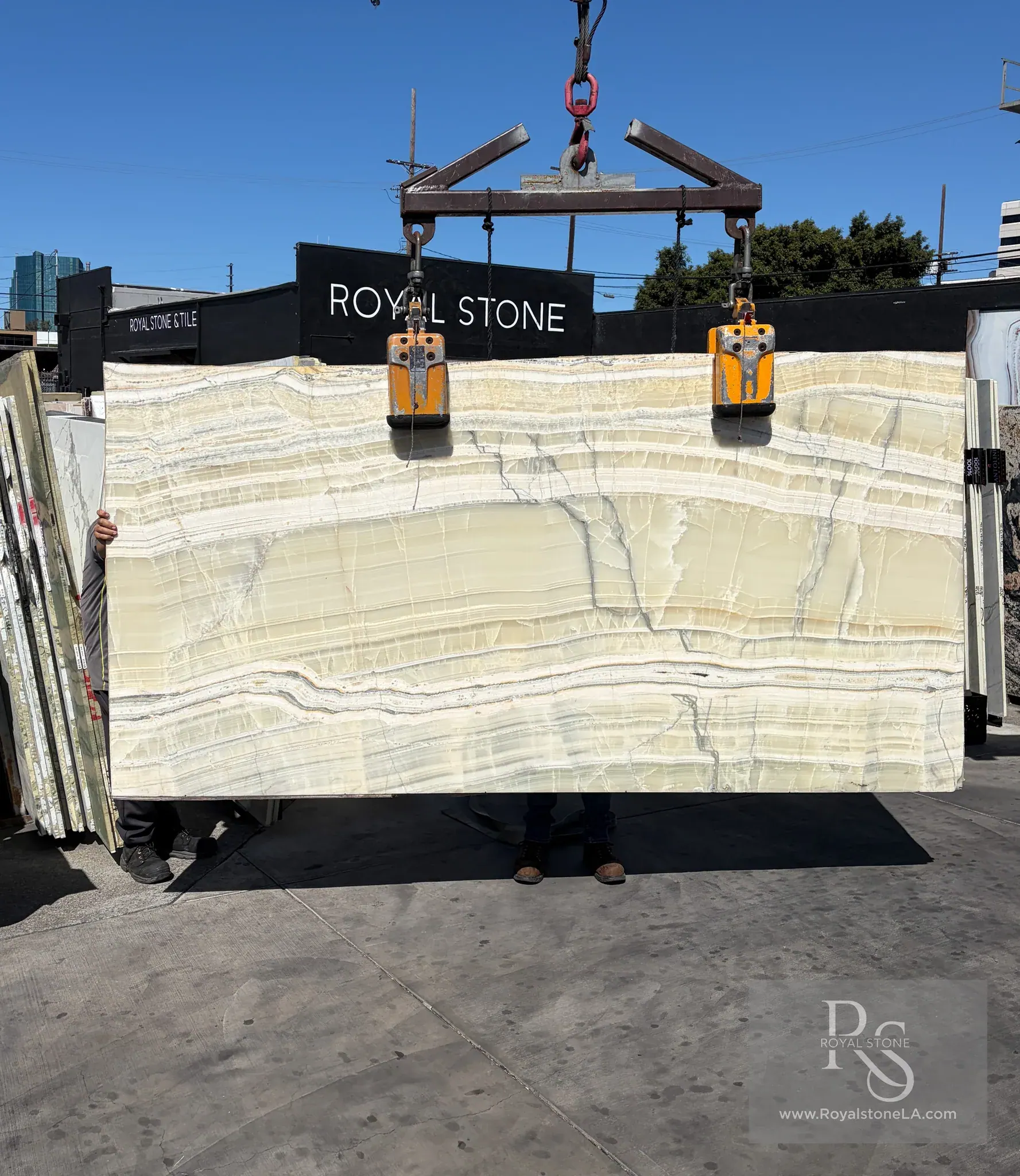 Vanilla Sage vein-cut onyx slab polished at 62 by 114 inches lifted on the crane at Royal Stone Los Angeles, translucent cream and pale celadon stratified body