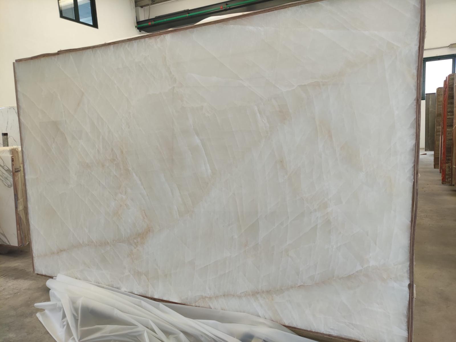 White Onyx Select Onice Bianco slab in the Royal Stone warehouse, a closer view of the polished ivory body and translucent mineral structure
