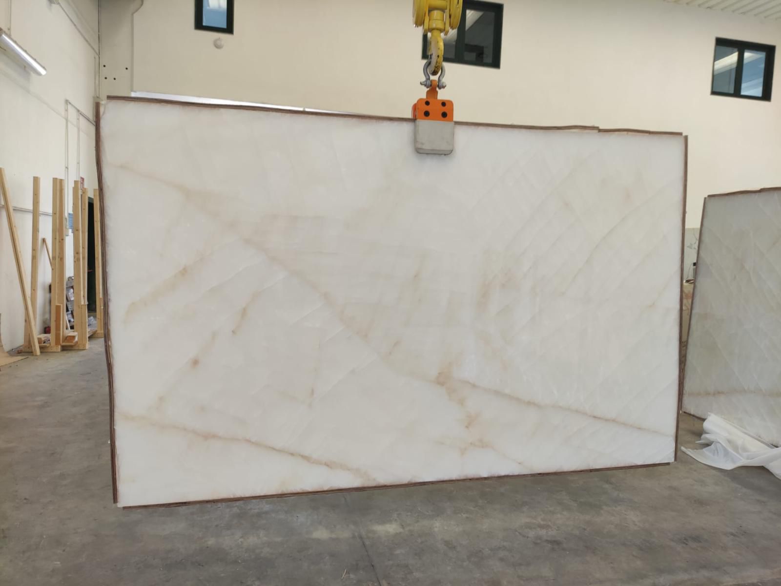 White Onyx Select Onice Bianco slab inside the Royal Stone warehouse, showing its polished ivory surface and soft translucent banding