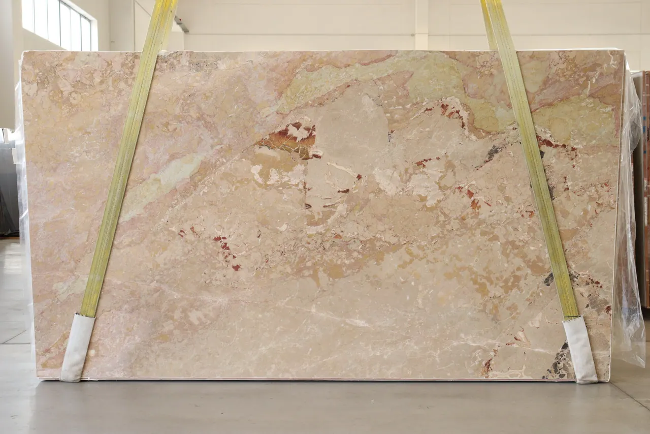 Ceppo Quattro Stagioni Libeccio honed marble slab strapping at the factory — warm cream and beige field broken by brecciated fragments of rust, ivory, and pale grey, lot 9048