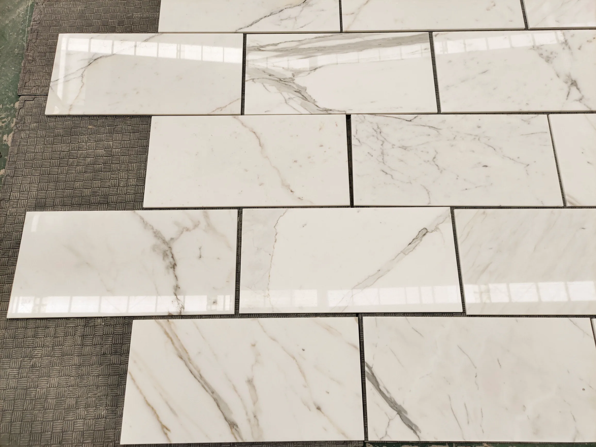Italian Calacatta Gold 12 by 24-inch marble tile samples being inspected during a client approval appointment on the Royal Stone dock