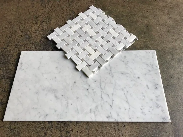 Honed Italian Carrara White marble basketweave mosaic sample above a honed field tile, on concrete