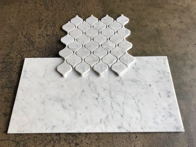 Honed Italian Carrara White marble lantern (arabescato) mosaic sample above a honed field tile, on concrete