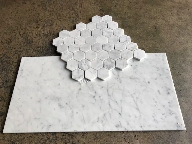 Honed Italian Carrara White marble 2-inch hexagon mosaic sample above a honed field tile, on concrete