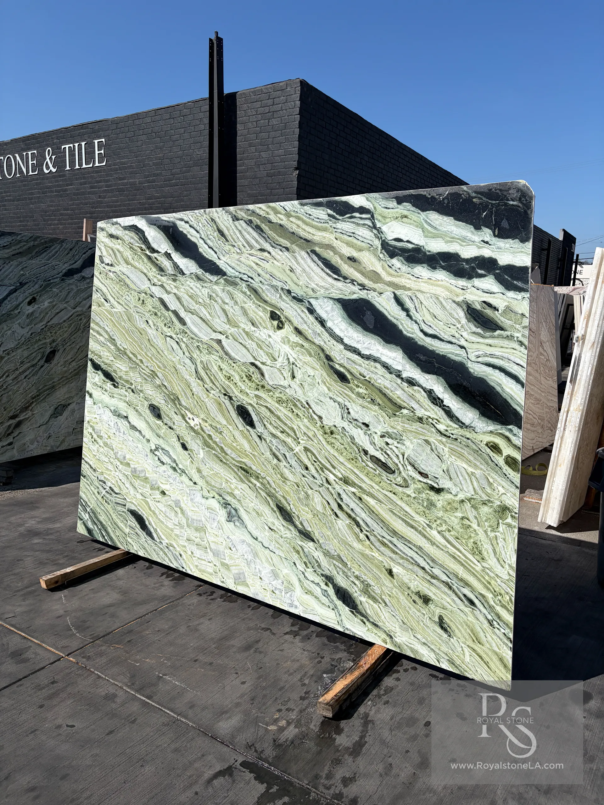 2cm Verde Van Gogh Green Beauty Dedalus polished marble slab, 71 by 110 inches, swirling sage-green field crossed by charcoal-black and ivory currents, standing in the Royal Stone yard in Los Angeles