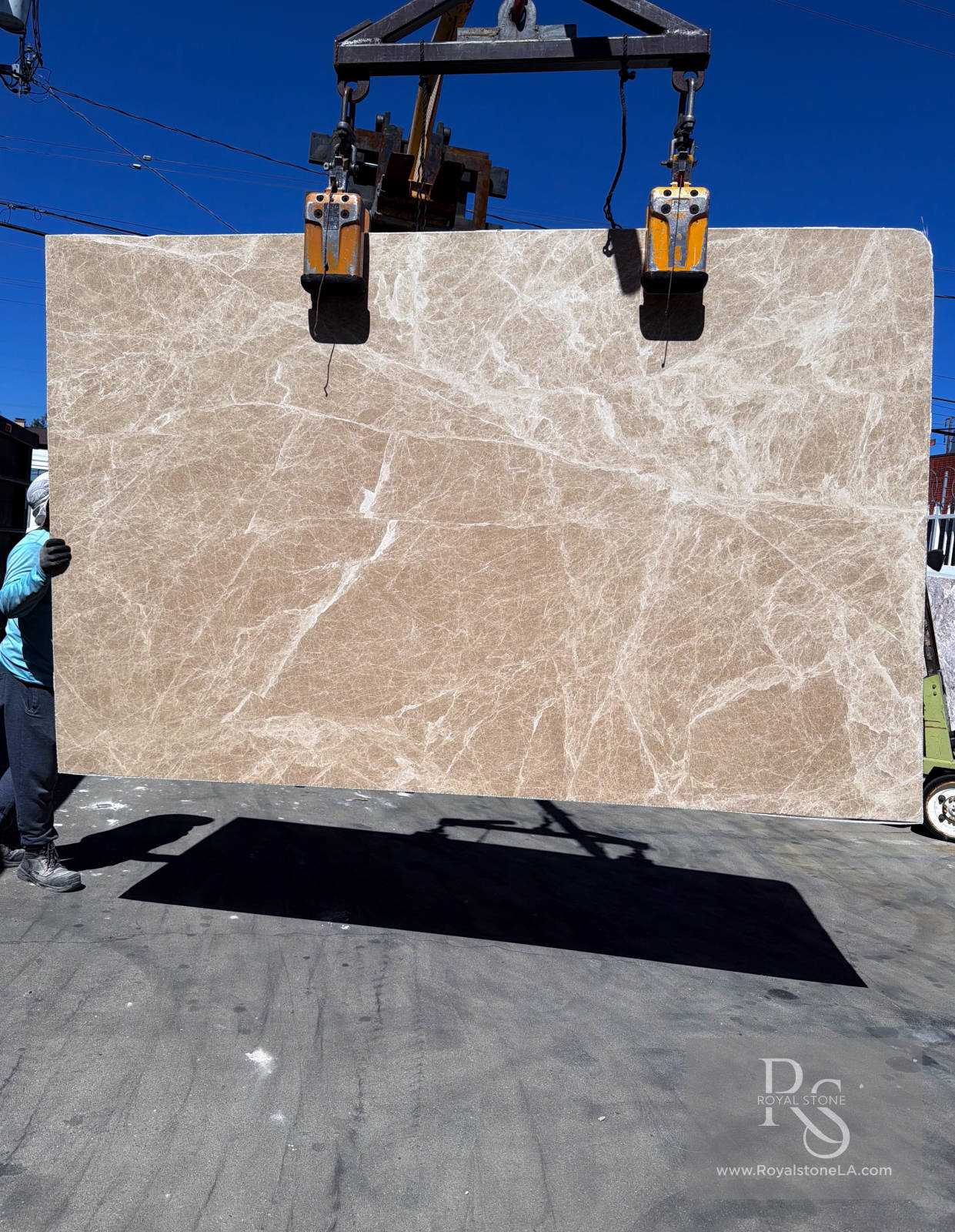 2cm Petris Light Emperador Select honed marble slab, 75 by 118 inches, warm taupe-beige field with fine alabaster veining, lifted by crane at Royal Stone slab yard in Los Angeles