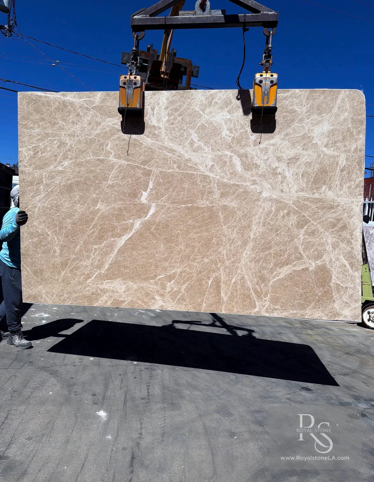 2cm Petris Light Emperador Select honed marble slab, 75 by 118 inches, warm taupe-beige field with fine alabaster veining, lifted by crane at Royal Stone slab yard in Los Angeles