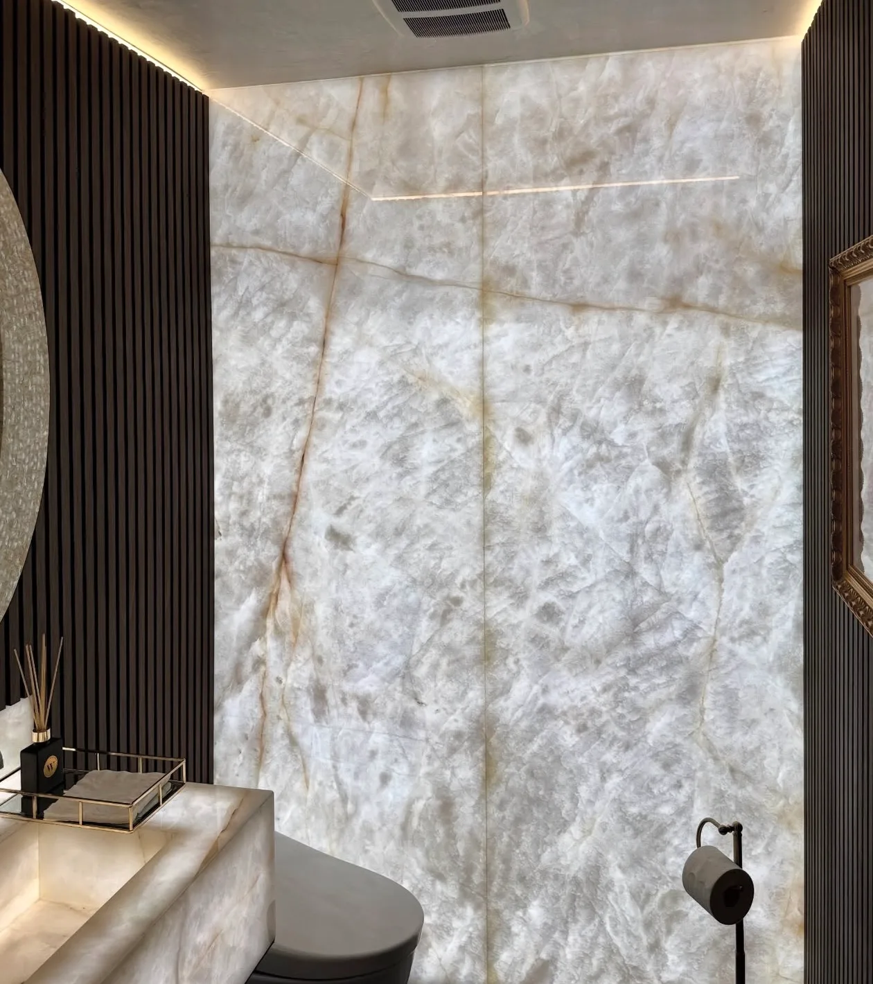 Powder room with backlit Cristallo quartzite slab walls and matching carved stone vanity.