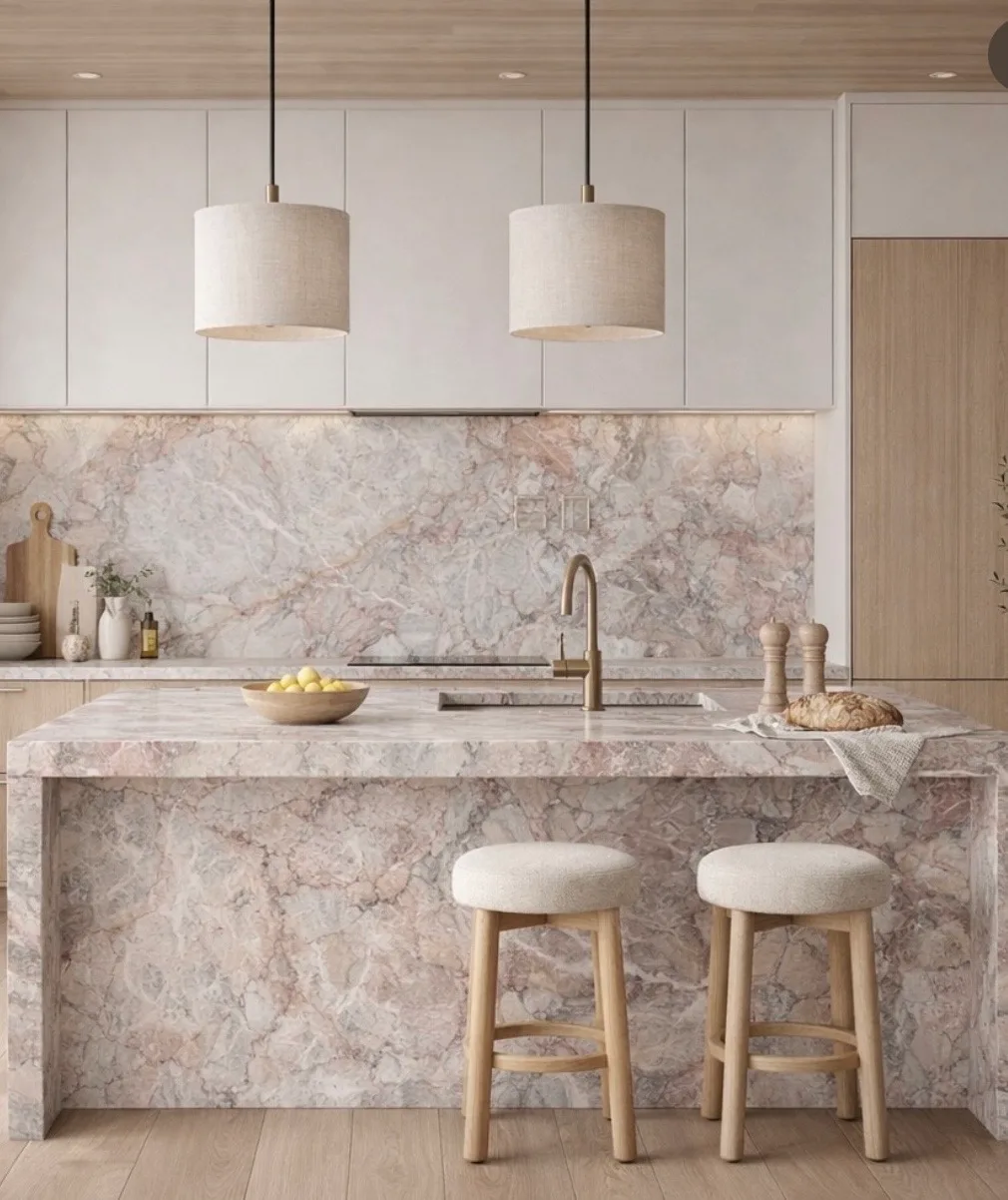 Kitchen island and full-height backsplash in soft rose-and-cream quartzite with waterfall edges.