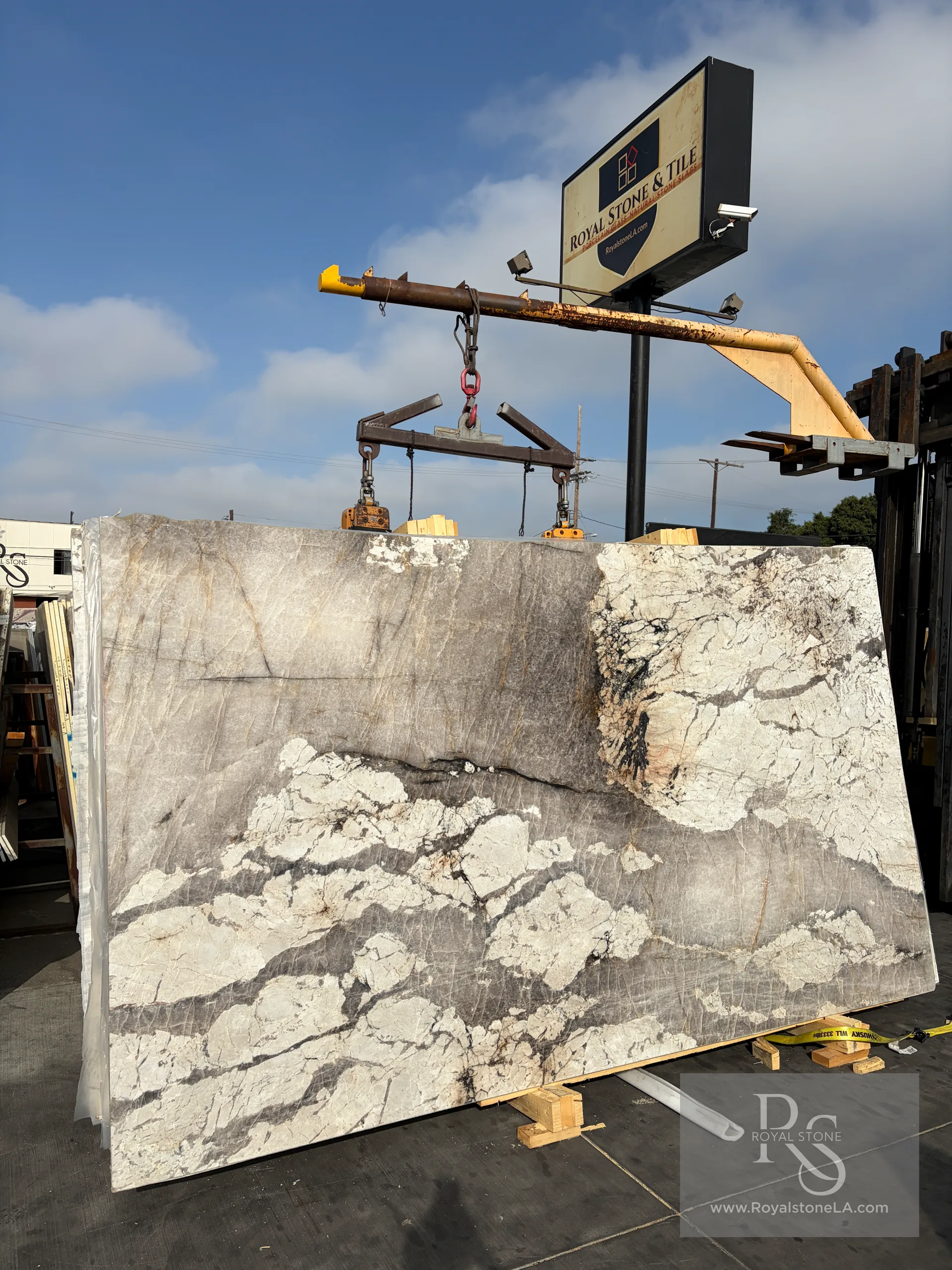 2cm Patagonia Alabastro honed quartzite slab, 80 by 138 inches, full yard view lifted on overhead crane with the Royal Stone & Tile yard sign and Italian-cut cloud formations visible, in Los Angeles