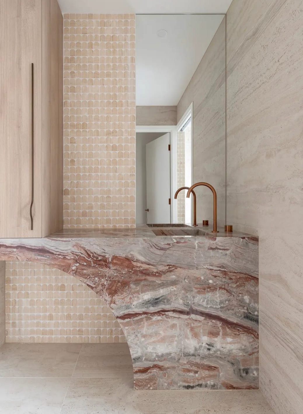 Viola Orobico marble carved into a sculptural powder room vanity with travertine wall and arched mosaic tile surround
