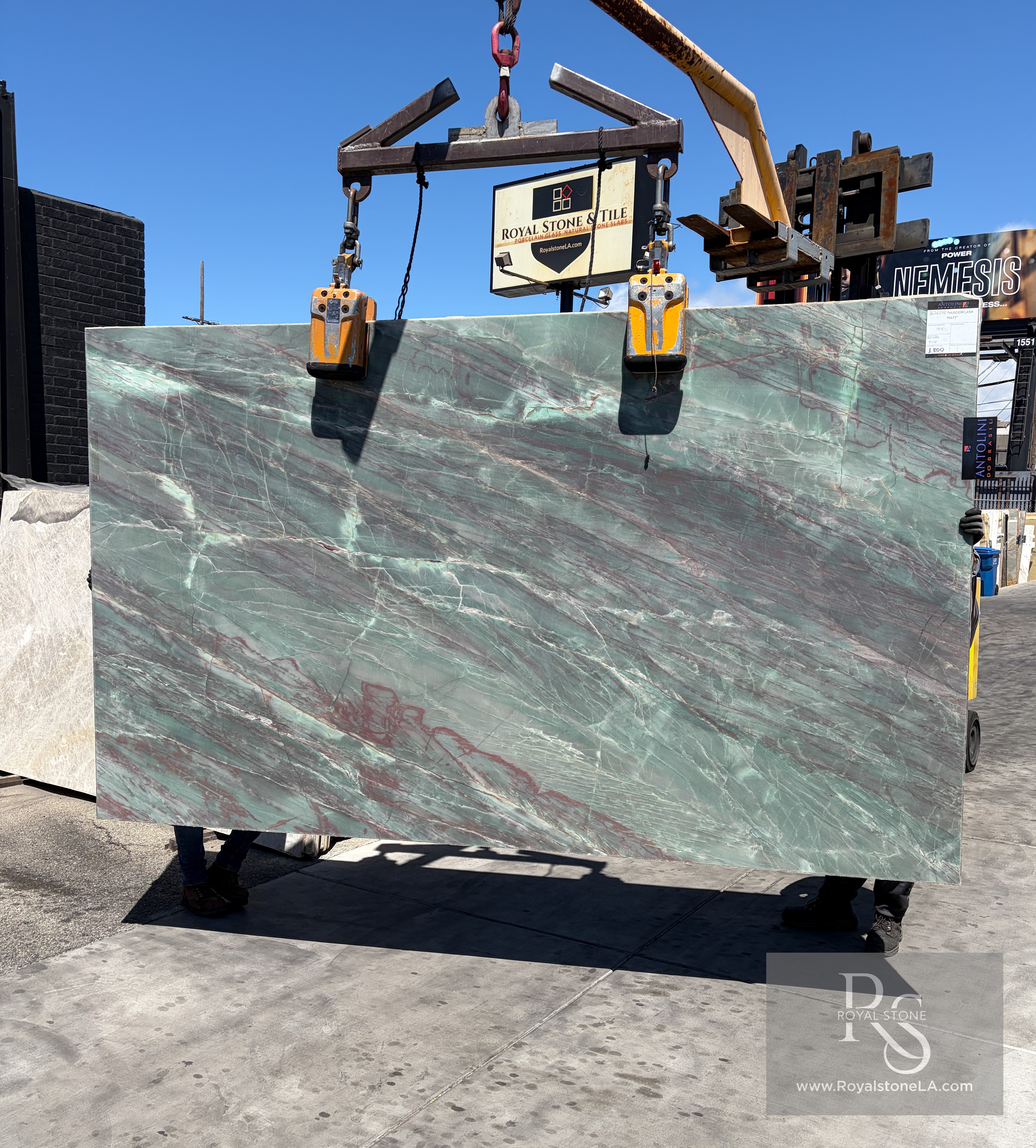 Antolini Thunderflash green quartzite slab, 2cm honed, 76 by 129 inches, with matte seafoam-green field and softened garnet and copper veining, hanging from a crane at the Royal Stone Los Angeles yard