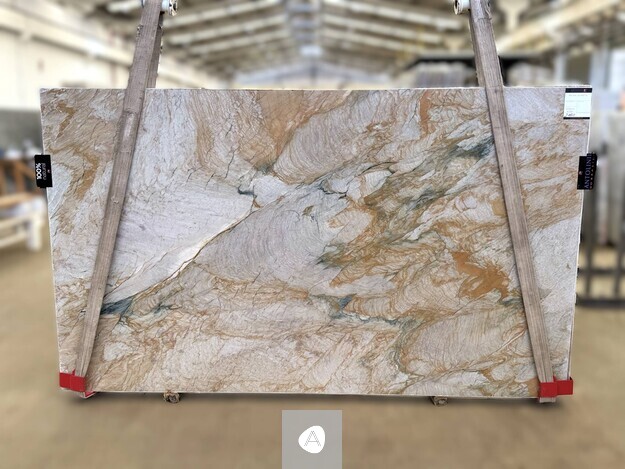 Antolini Mistral quartzite slab with sandy cream field, gold currents, and faint teal pockets, polished