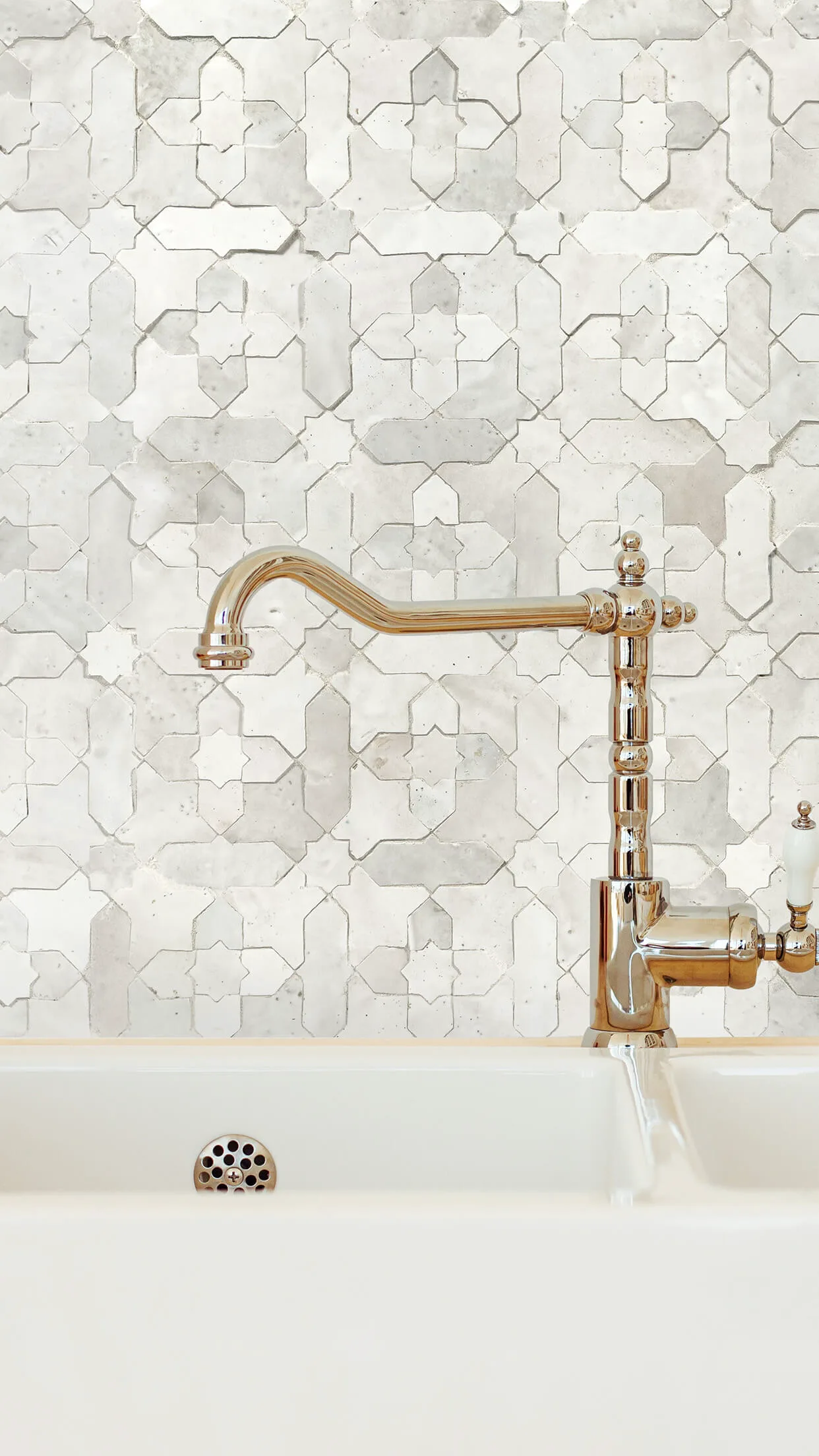 Zellige Classique star and cross pattern tile backsplash under a brass wall faucet